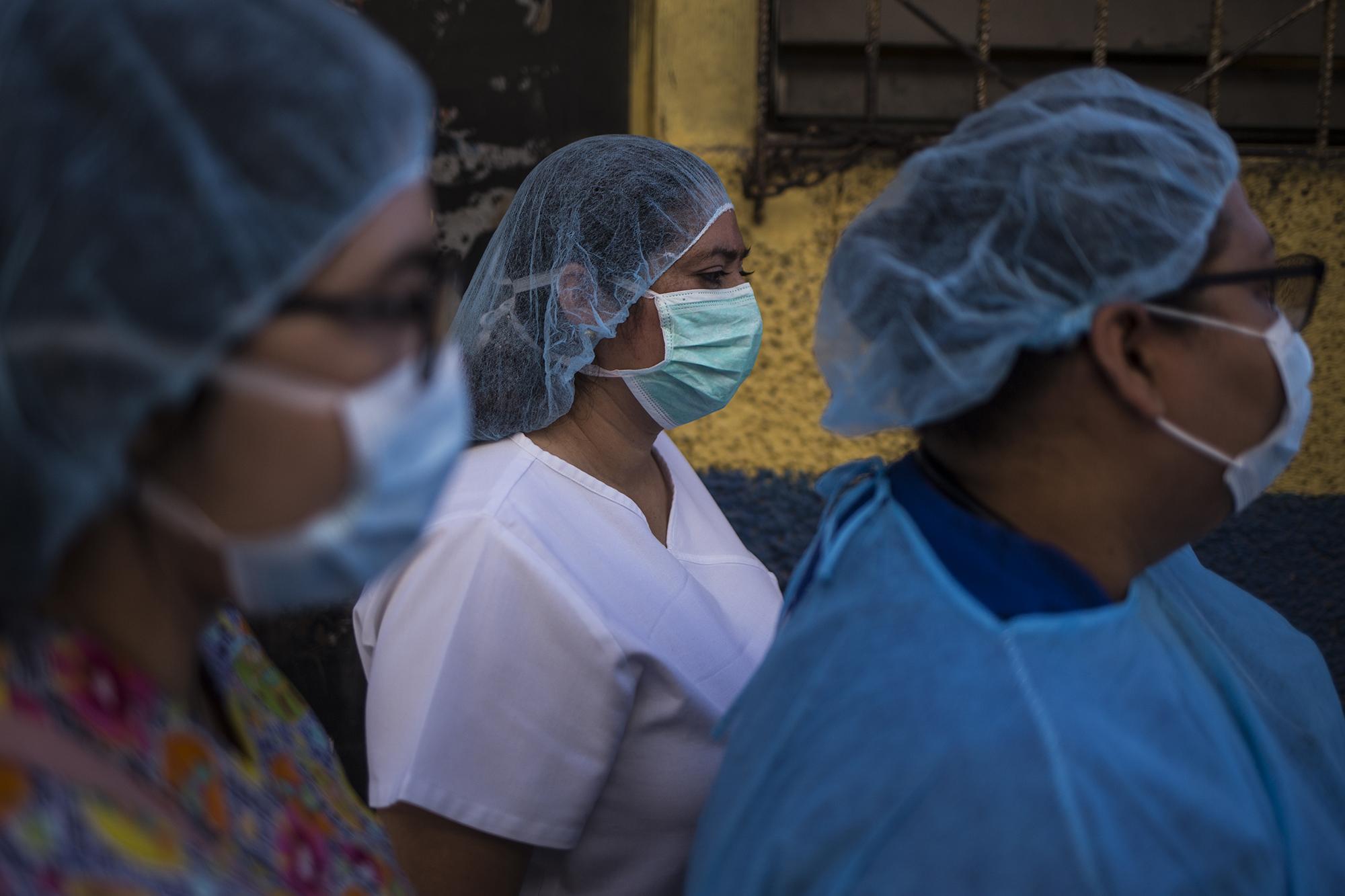 Personal médico de la alcaldía de San Salvador durante campaña de desinfección en el mercado La Tiendona, en San Salvador. Foto de El Faro: Víctor Peña.