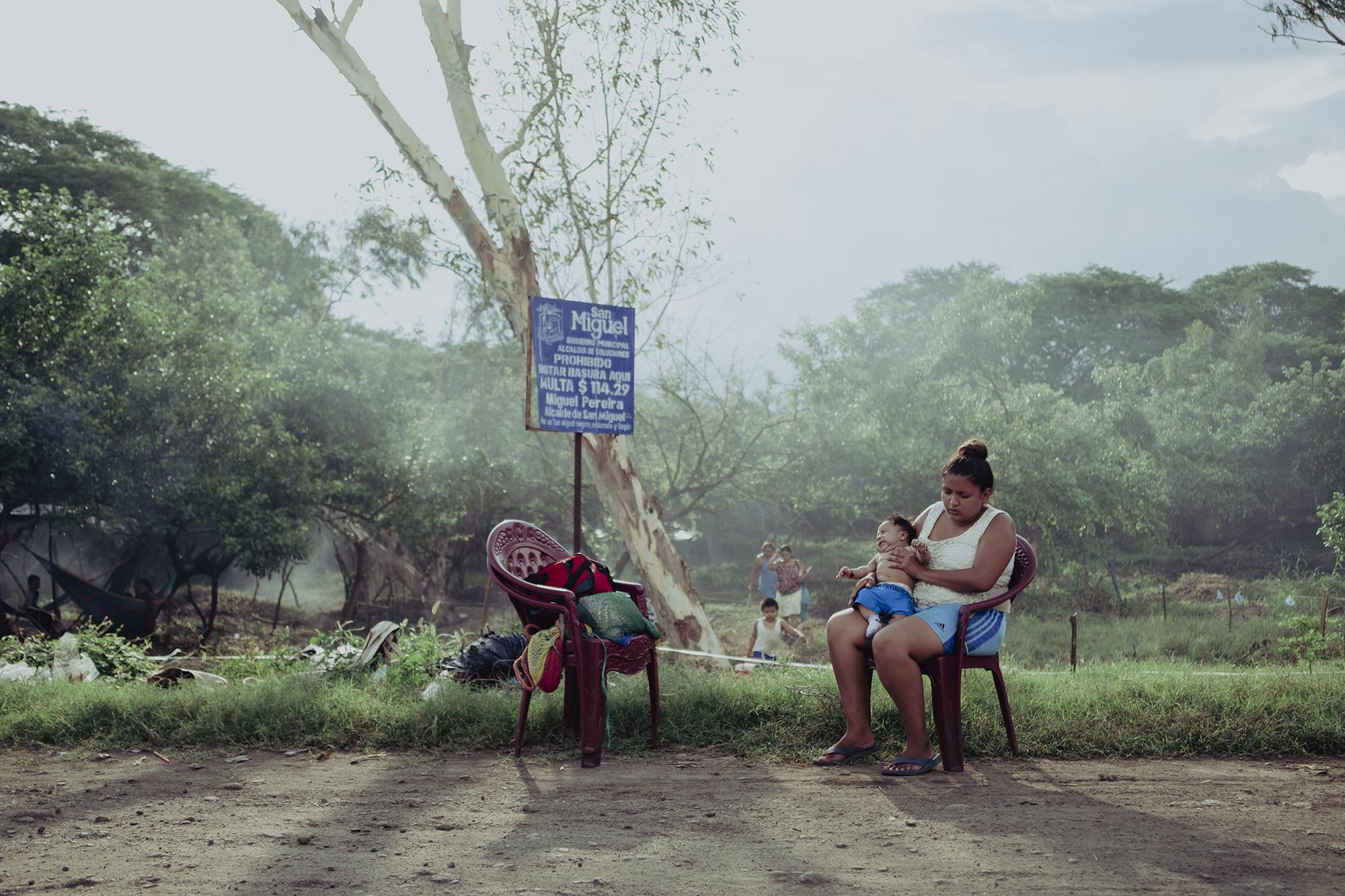 Stefany Gómez rests with her son in the shade of a tree on a plot of land near the Río Grande of San Miguel. While she takes care of her son, her partner washes cars in town. Of their monthly earnings of $250, they paid $75 to rent a room prior to Covid-19. Since the start of the pandemic, Stefany gave birth and her husband wound up unemployed. With a newborn at home and the fallout of the quarantine, they decided to leave their old home in search of a place where they could save money and start fresh. 
