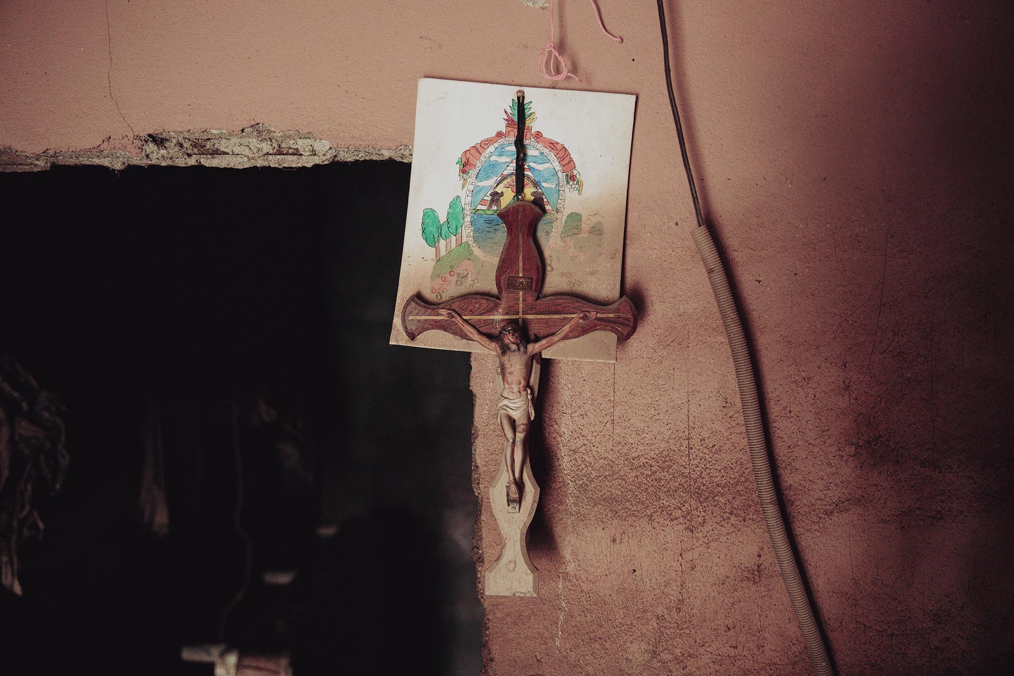 Marca de lodo seco sobre un escudo de Honduras y un crucifijo muestra el nivel que alcanzó el agua en la aldea La Gálvez, en Bajos de Choloma. Los habitantes de esa aldea tuvieron que subir a los techos para sobrevivir y luego ser rescatados en lanchas.