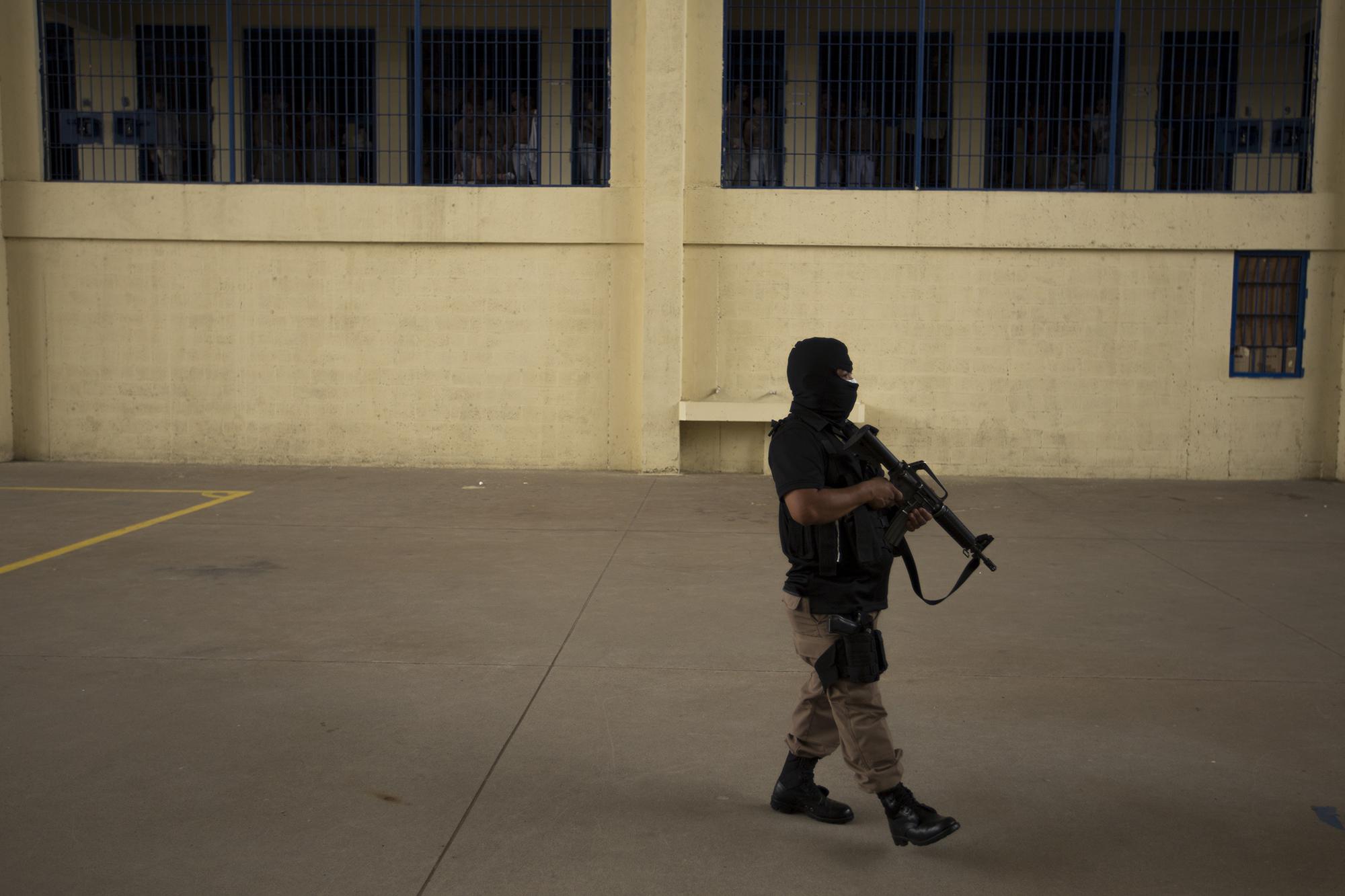 A prison guard walks through a sector of the maximum-security wing of Izalco during an official visit by the director of prisons, Osiris Luna. Photo: Víctor Peña/El Faro