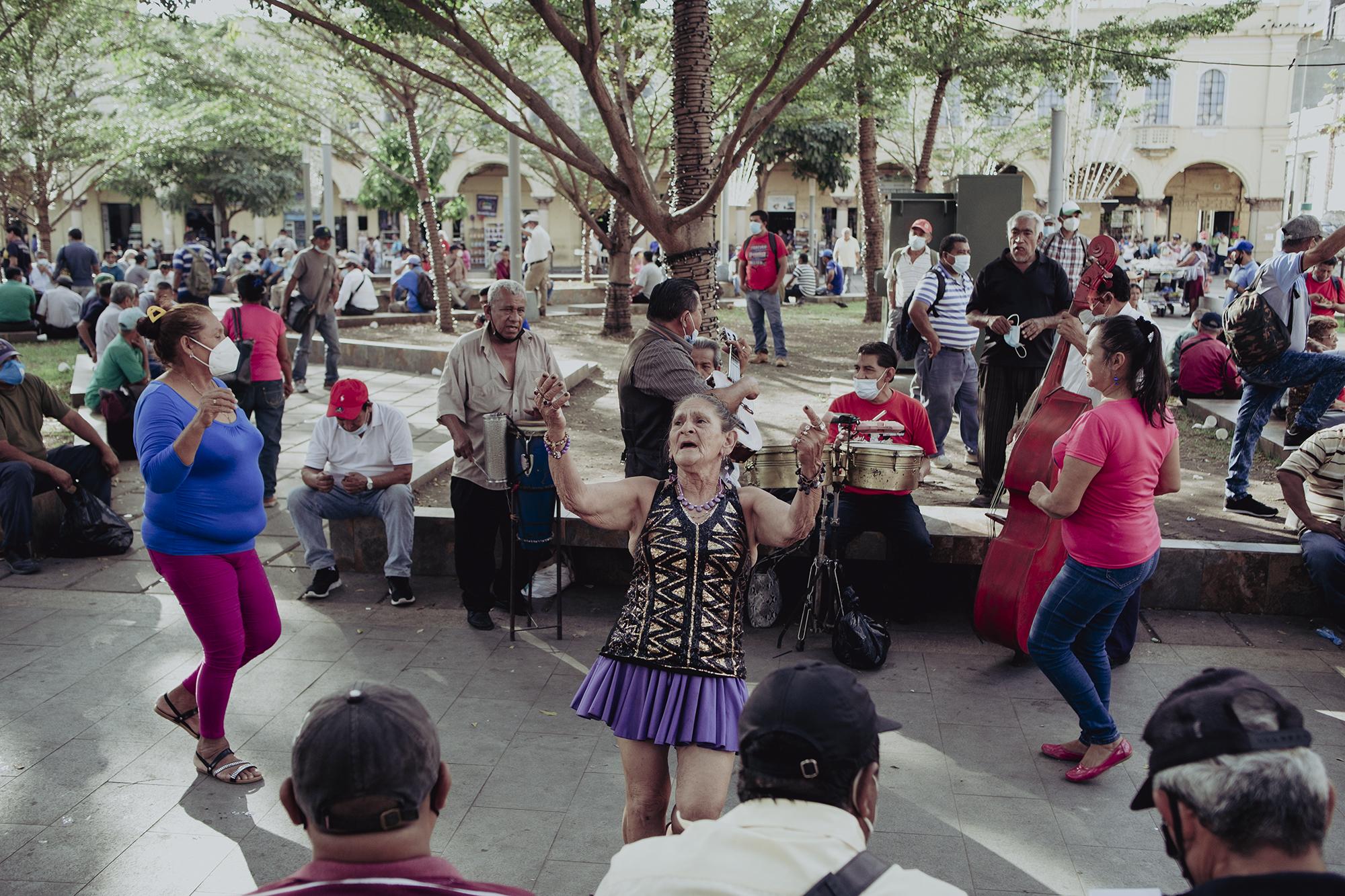 Decenas de personas se acumulan en la plaza Libertad de San Salvador, muchos llegan por ocio y otros por trabajo, como Zoila Isabel Aguilar, una bailarina muy reconocida del lugar, que, acompañada de un grupo musical entretienen a las personas para poder ganar unas monedas, 