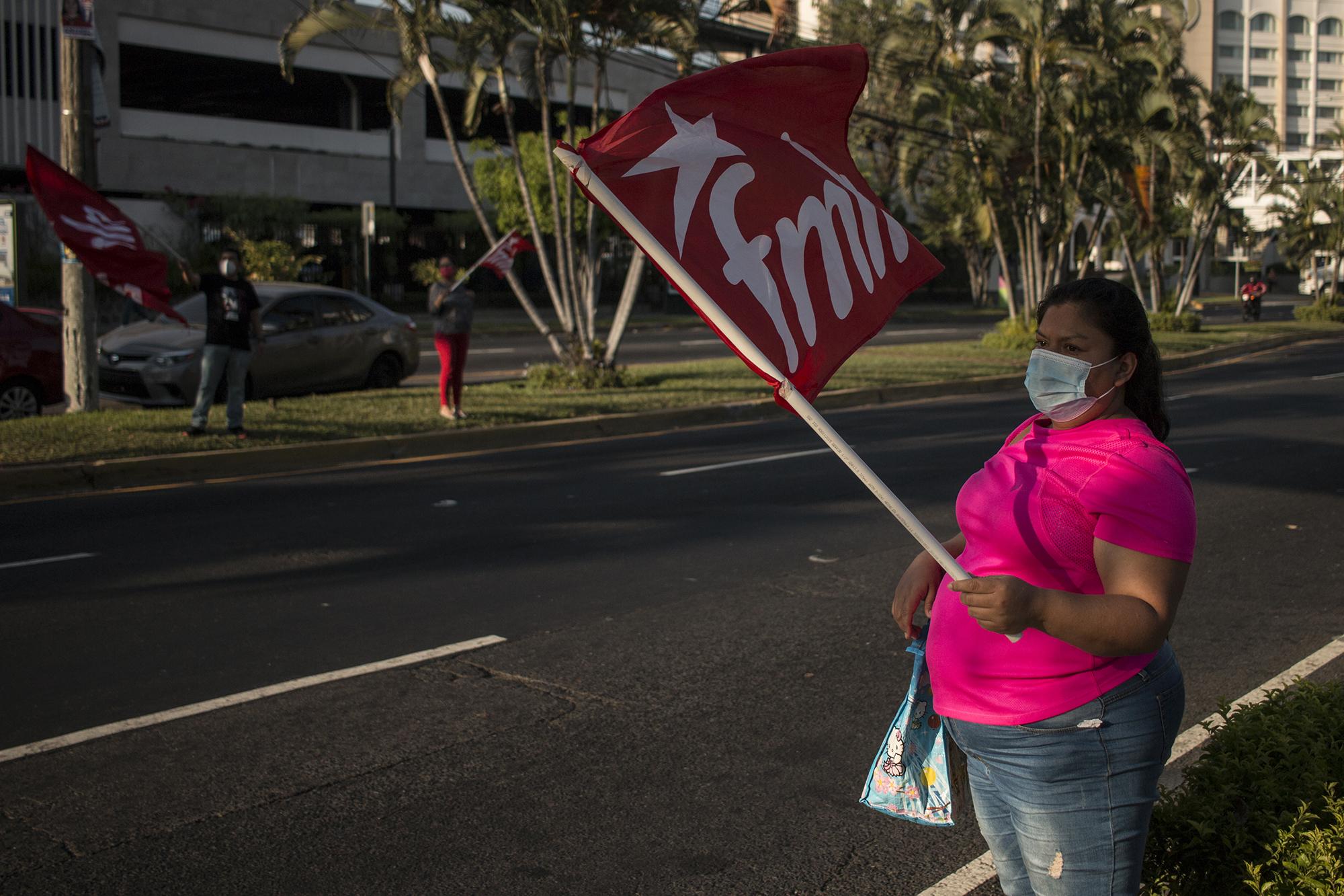 Militantes del FMLN ondean banderas sobre el bulevar Los Héros en San Salvador, el 7 de febrero de 2021. Estas actividades eran realizadas con personal de la Asamblea Legislativa que trabaja para el partido de izquierda. Foto de El Faro: Víctor Peña. 