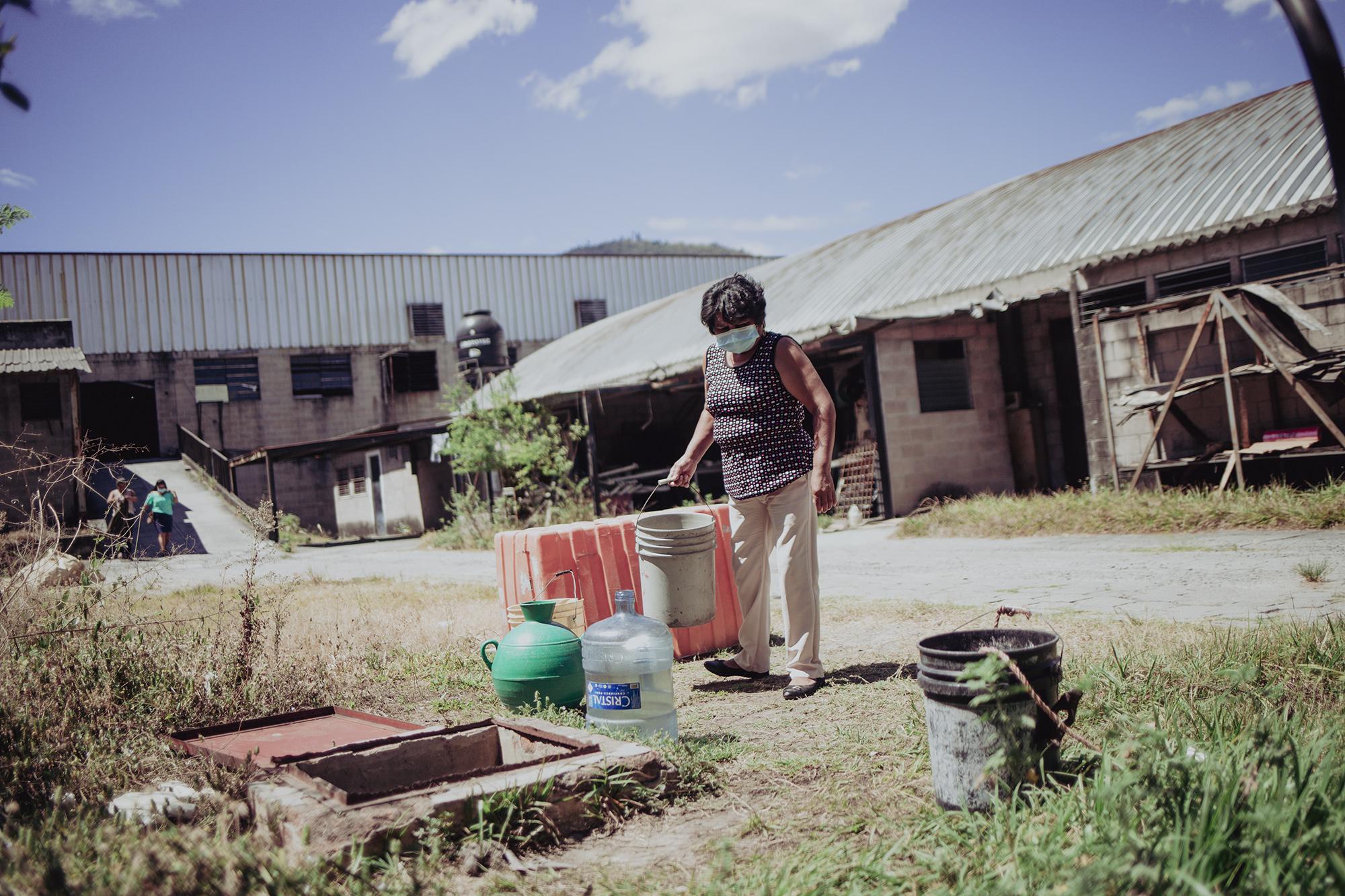 Rosario Sandoval, de 58 años, saca agua de una cisterna en un predio de la fábrica. El agua es utilizada para actividades de primera necesidad. Las instalaciones carecen de agua potable. La cisterna se llena por pipas que pagan organizaciones, personas solidarias y la Alcaldía de Soyapango.