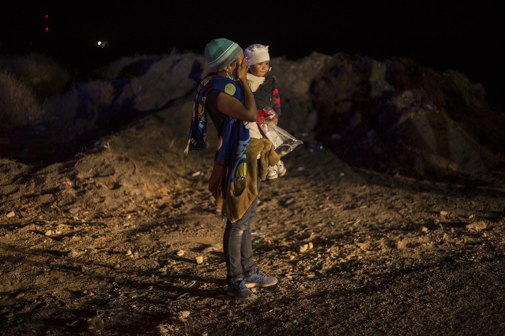 A woman carries her son in her arms in front of Border Patrol agents. She, too, emerged from hiding in the brush to turn herself in. “I already feel relieved to be here,” she told an agent who received her. The agents on patrol didn’t take the time to talk to each of the detained migrants.