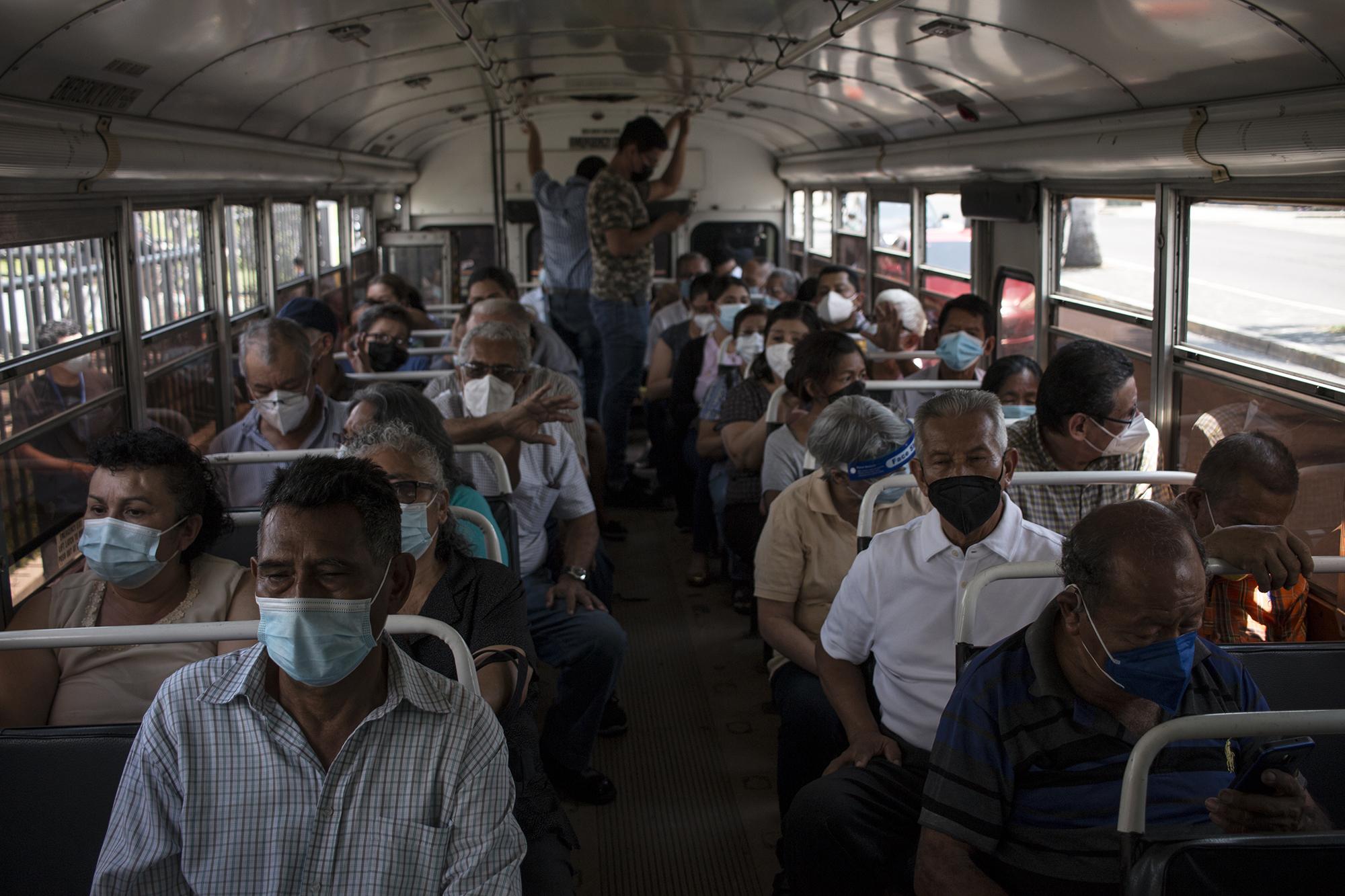 Después de las aglomeraciones, el Gobierno contrató autobuses de emergencia para trasladar a los beneficiarios. Aquí, más de cincuenta personas son trasladadas en un bus del transporte colectivo de la ruta 30. Foto de El Faro: Víctor Peña. 