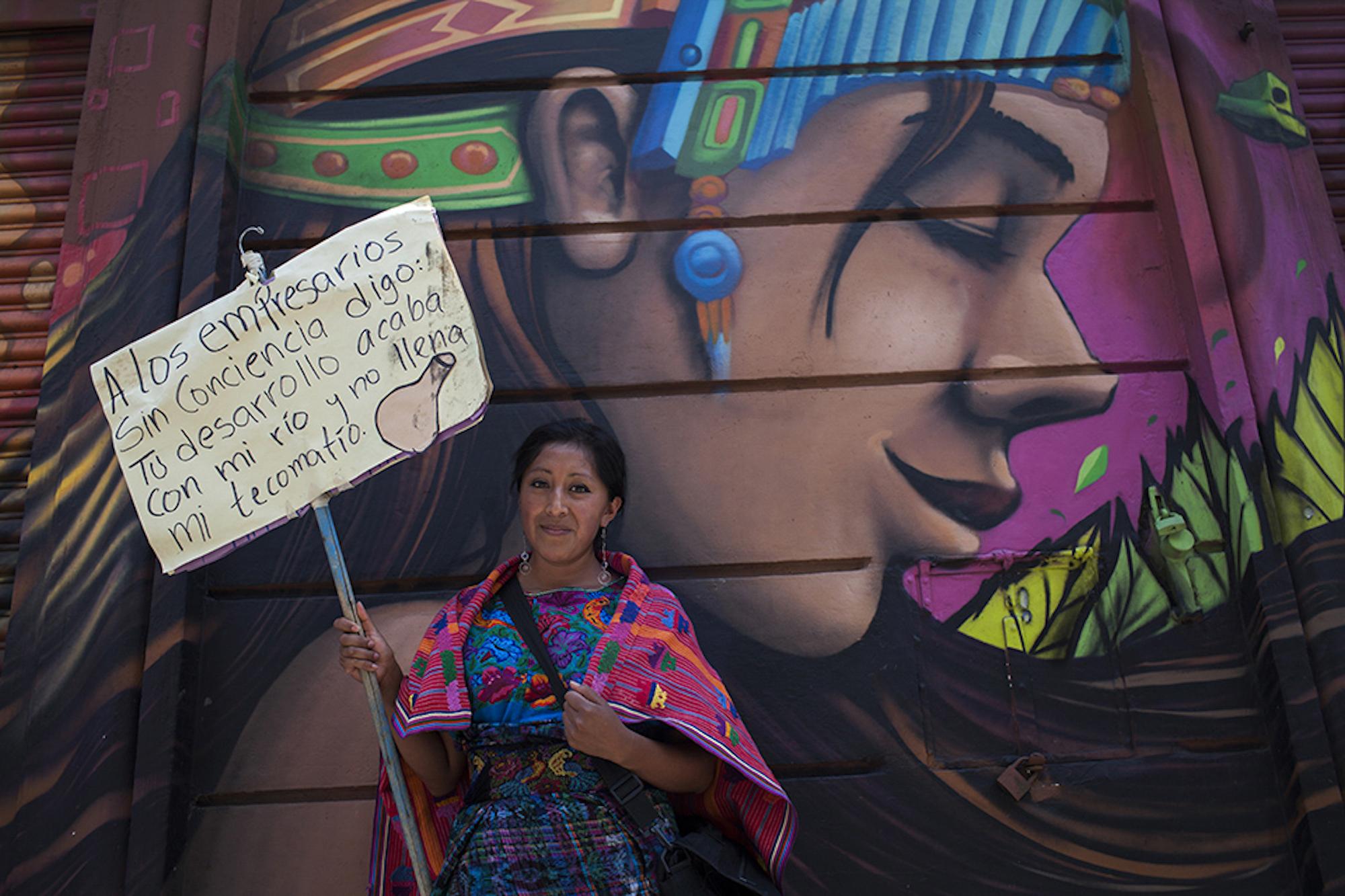 An Indigenous woman holds up a protest sign protesting the diversion of rivers, during the 2016 water march: “To the businessmen with no conscience, I say: Your development puts an end to my river and doesn’t fill my canteen.” Photo: Simone Dalmasso/Plaza Pública