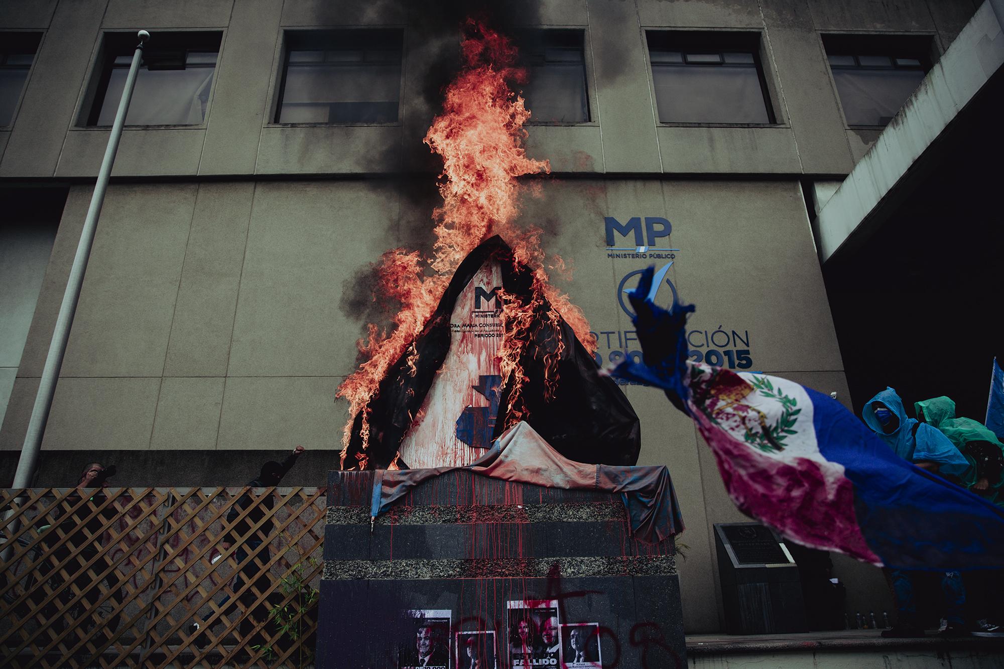 Durante la manifestación un grupo de personas le puso gasolina a un monumento con el símbolo de Ministerio Público en la Ciudad de Guatemala, allí se concentraron todas las marchas que entraron de distintos puntos a la capital. Foto de El Faro: Carlos Barrera