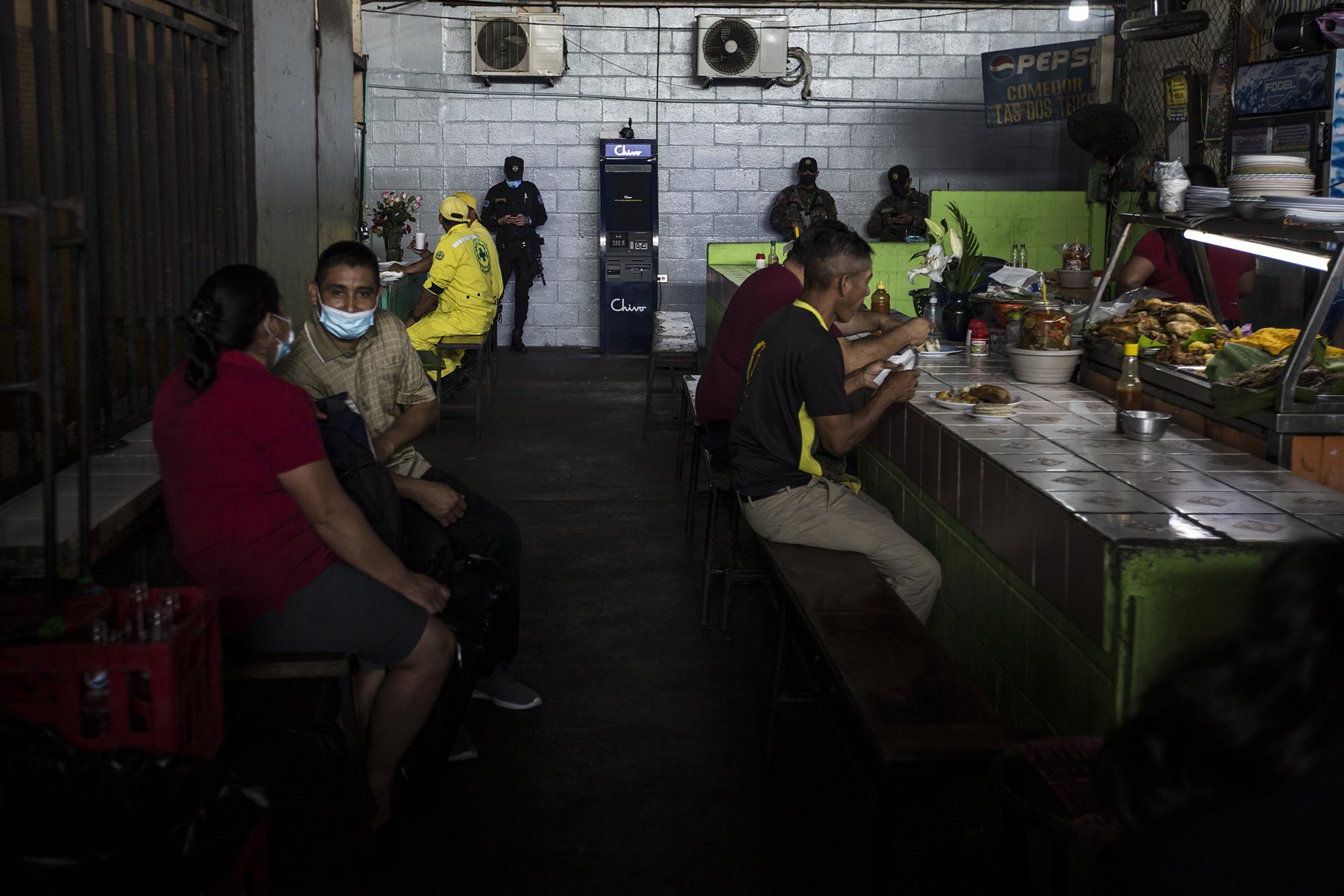 Militares y policías custodian un cajero Chivo instalado cerca del área de comedores del mercado municipal de Santa Tecla, en el departamento de La Libertad. 