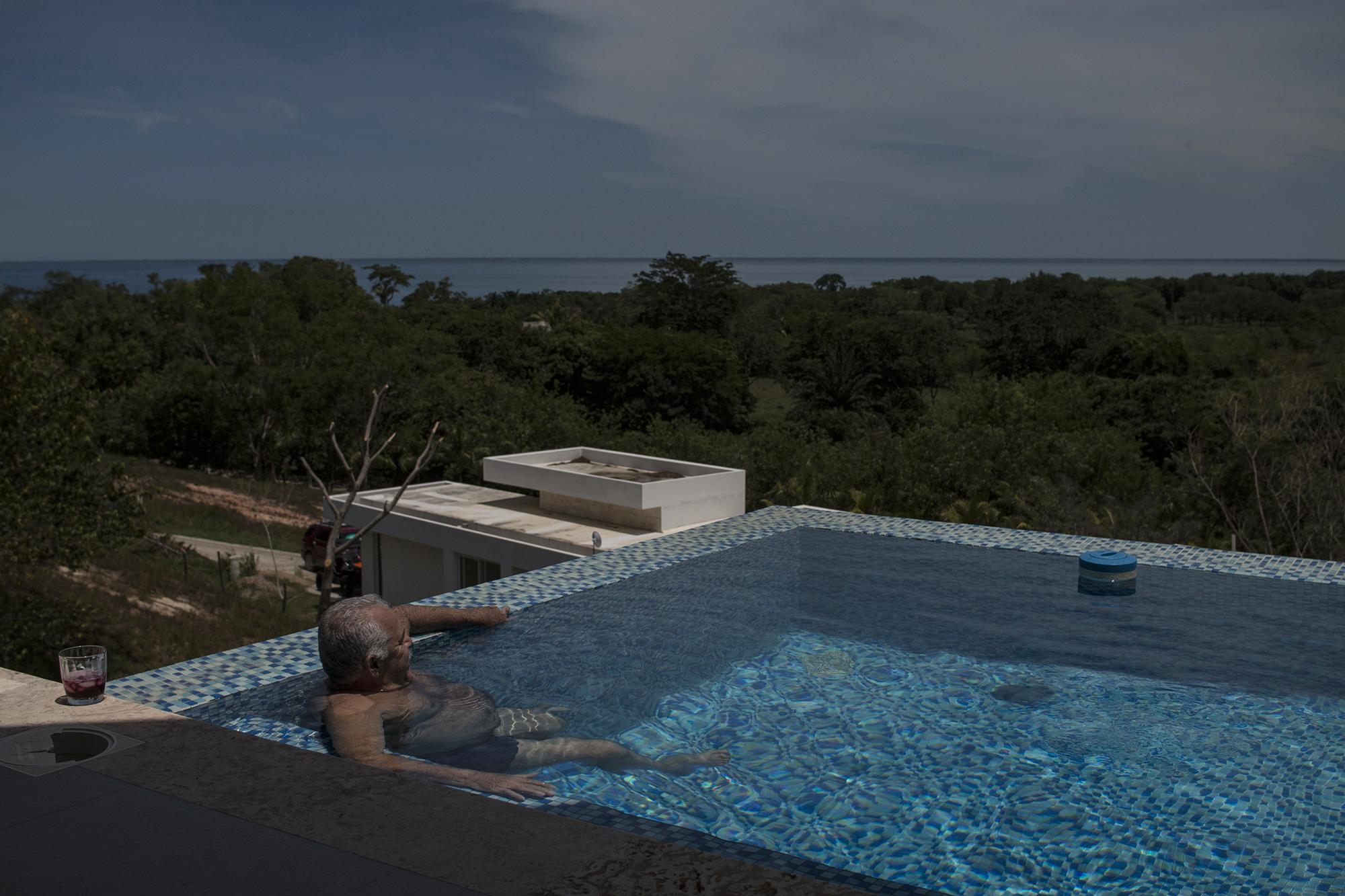 Óscar Nájera observa el mar Caribe desde su piscina en el complejo privado NJOI, al que se llega por calles polvosas. Está ubicado en medio de las comunidades garífunas que rodean el municipio de Trujillo, en Colón, Honduras. Foto de El Faro: Víctor Peña.   