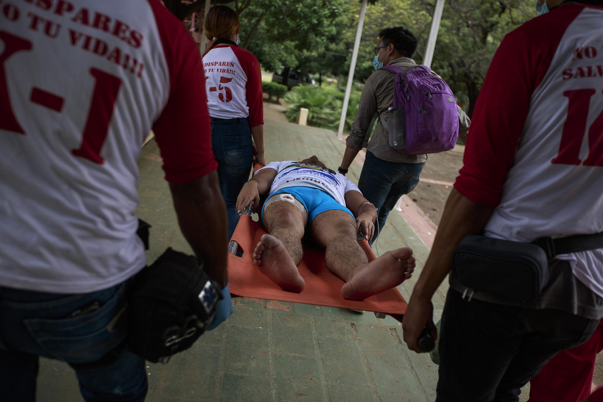 A rebel medical brigade tends to a man with a bullet wound on university grounds. The man was wounded during a march that was attacked by unknown assailants. Another man, 23, who had sold handkerchiefs and flags at the march, died of a bullet wound to his forehead. June 30, 2018.