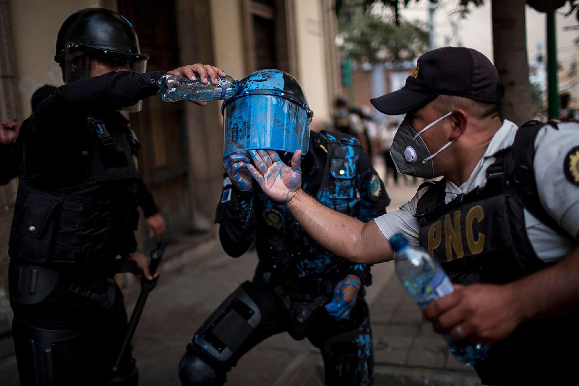 Un policía antimotín es auxiliado después de haber sido golpeado por manifestantes contra el congreso y el gobierno de Guatemala. Foto: Simone Dalmasso/Plaza Pública
