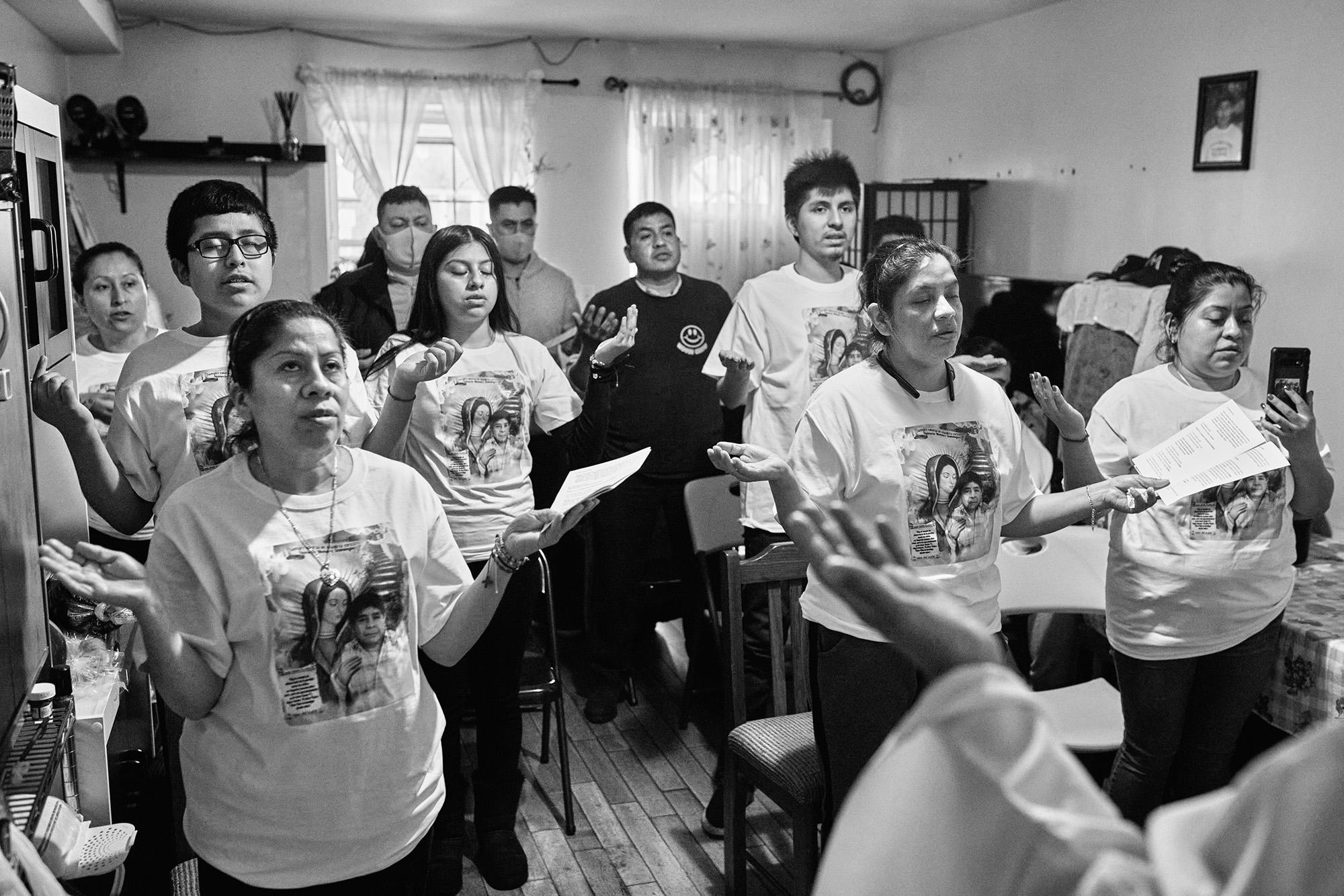 The Méndez family holds Mass in their living room in Corona, Queens, to commemorate the one-year anniversary of the death of two family members, Nemesio and Gabriel, who fell ill and died of Covid-19. Photo: Edu Ponces/Ruido Photo