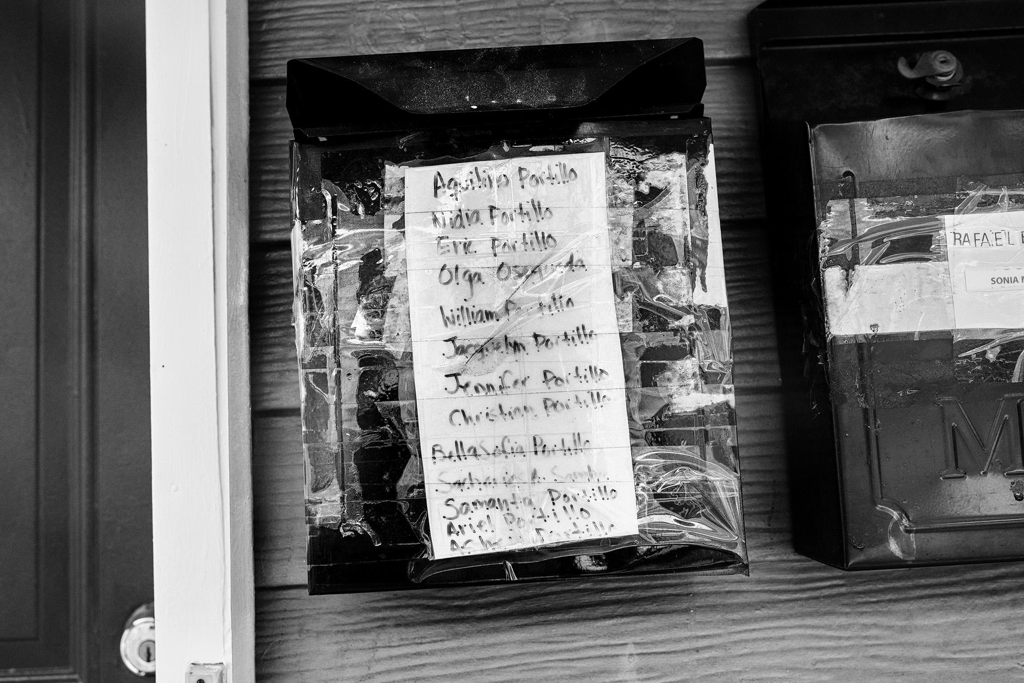 The names of the 13 members of the Portillo family are handwritten on their mailbox in New Jersey, a state home to more than 50,000 Salvadorans. Everyone in their home caught the virus and lost their jobs, leaving them in debt for more than $5,000 in mortgage payments. Photo: Edu Ponces/Ruido Photo