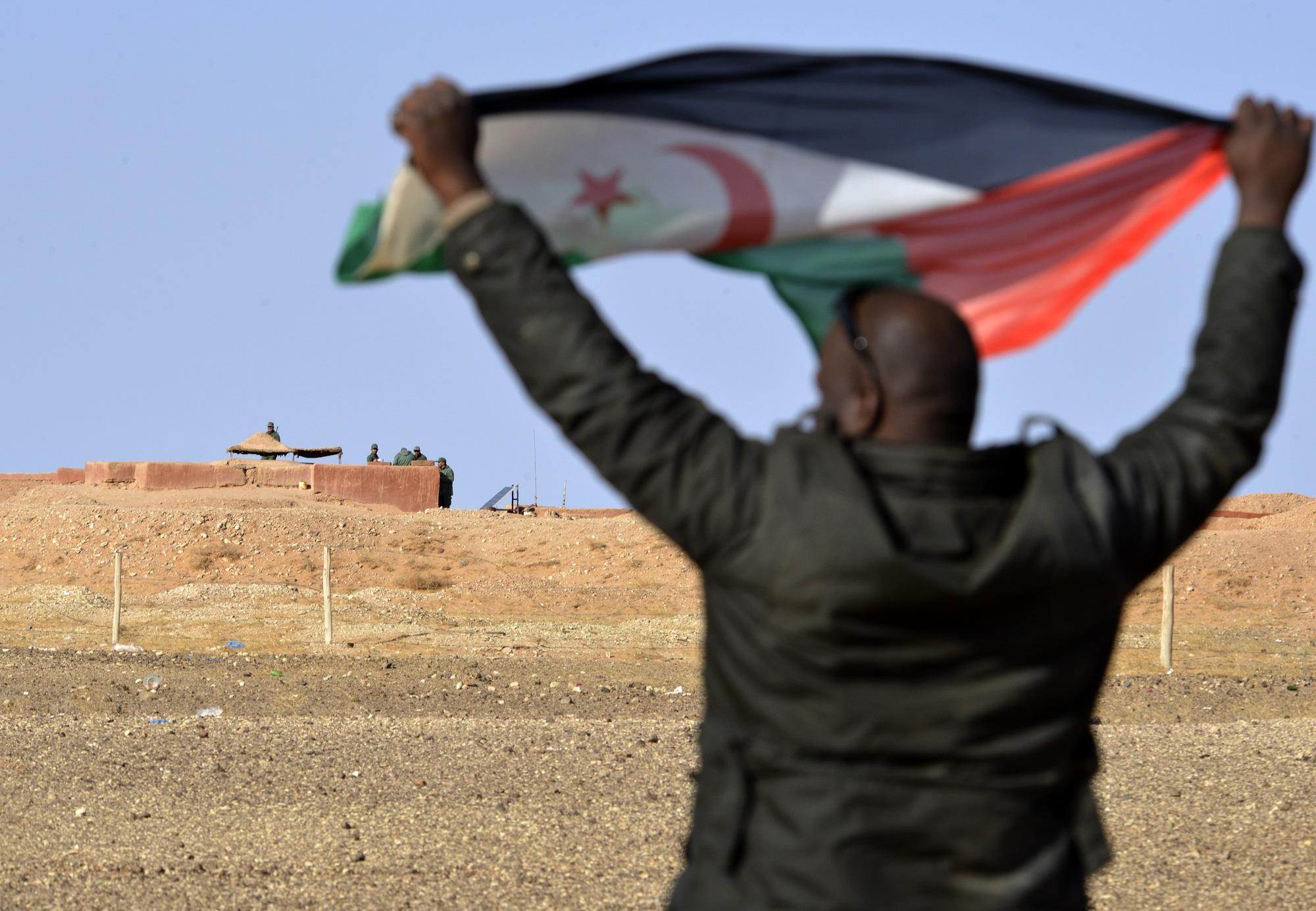 Un saharahui agita la bandera del Frente Polisario frente al muro construido por Marruecos, país que ocupa militarmente la mayor parte del Sáhara Occidental desde mediados de los setenta. Foto Ryad Kramdi (AFP).