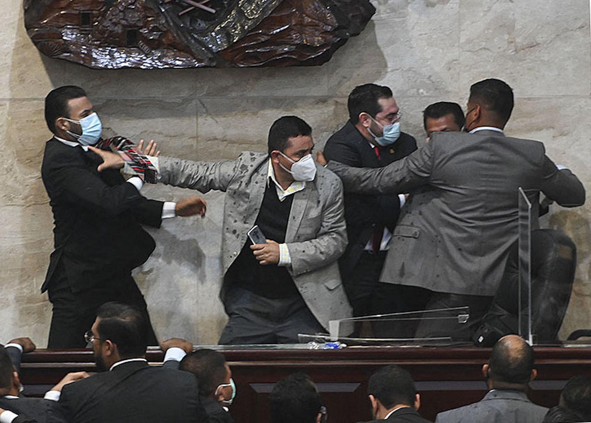 Deputy for the Libertad y Refundacion (LIBRE) party Rassel Tome (L) tries to assault deputy Jorge Calix (2-R) after his election as President of the Provisional Board of Directors of the National Congress, at the Legislative headquarters in Tegucigalpa, on January 21, 2022. Photo: Orlando Sierra/AFP