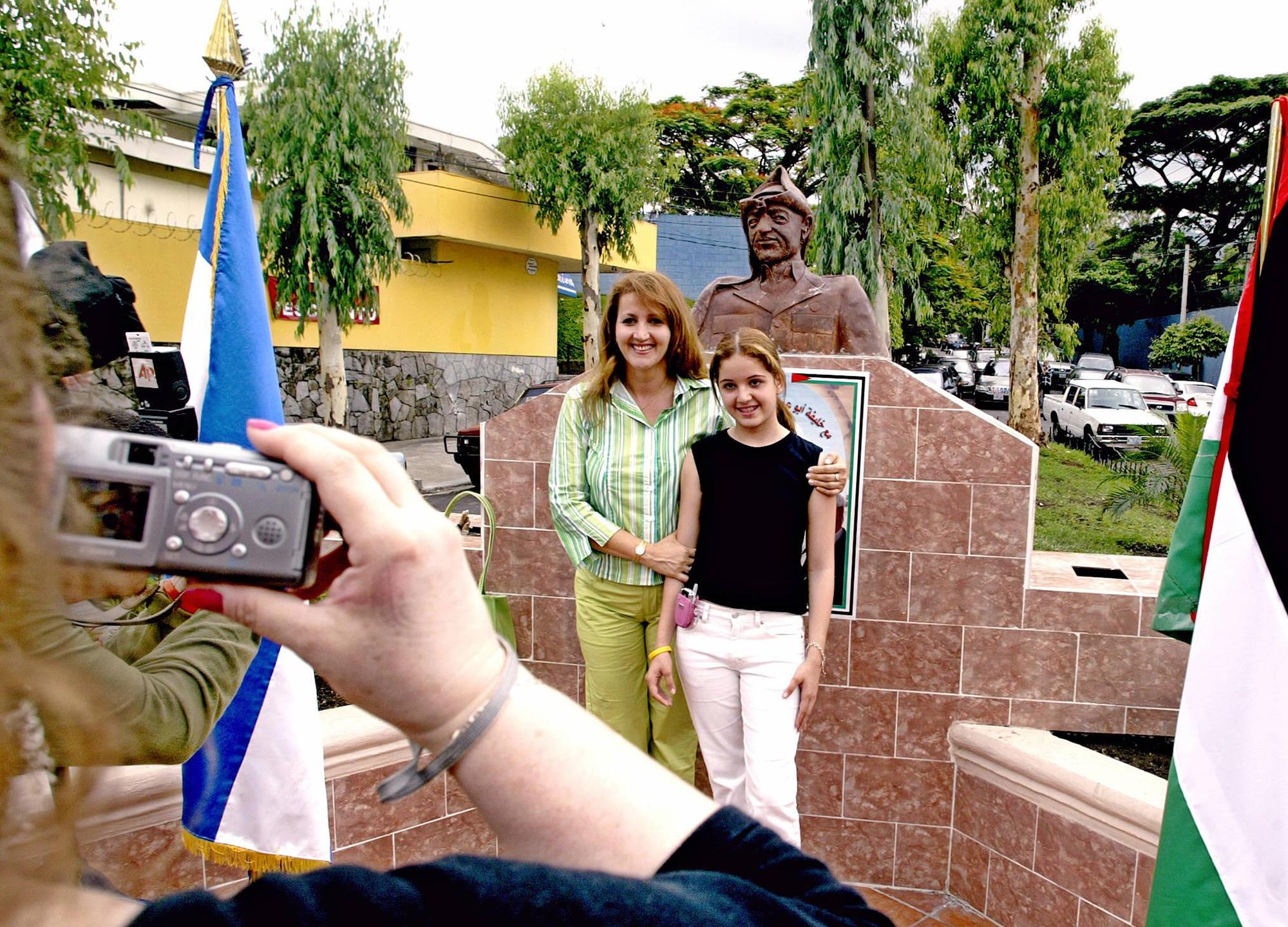 Madre e hija, salvadoreñas descendientes de palestinos, se toman una fotografía frente al busto de Yasir Arafat, en la plaza homónima ubicada en San Salvador. La imagen se tomó el 25 de mayo de 2005, día de la inauguración de la plaza en homenaje al polémico líder nacionalista palestino. Foto Yuri Cortez (AFP).