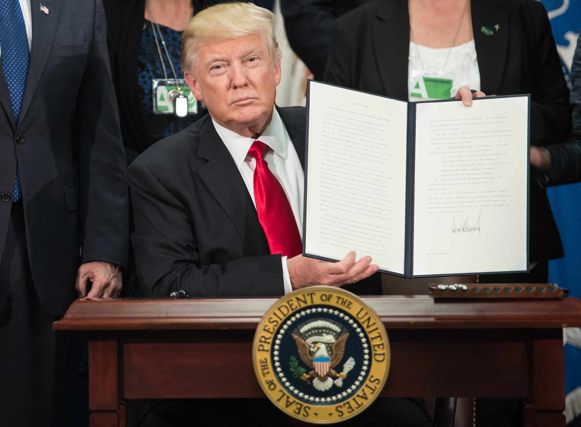 El presidente de Estados Unidos Donald Trump muestra a la prensa la orden ejecutiva firmada para la construcción del muro en la frontera sur de estados unidos. Enero 25 de 2017. Foto: Nicholas Kamm / AFP