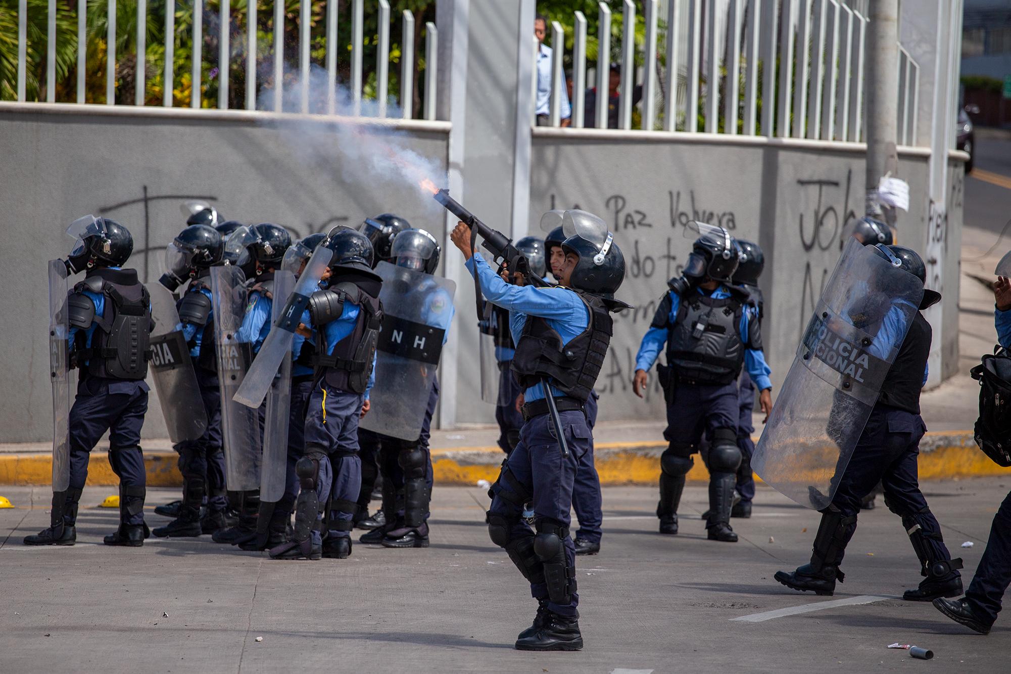 A National Police officer launches a tear gas bomb during a standoff with protesters calling for President Juan Orlando Hernández to step down after his brother was found guilty of drug trafficking in New York City. Tegucigalpa, October 25, 2019. Photo: Martín Cálix.