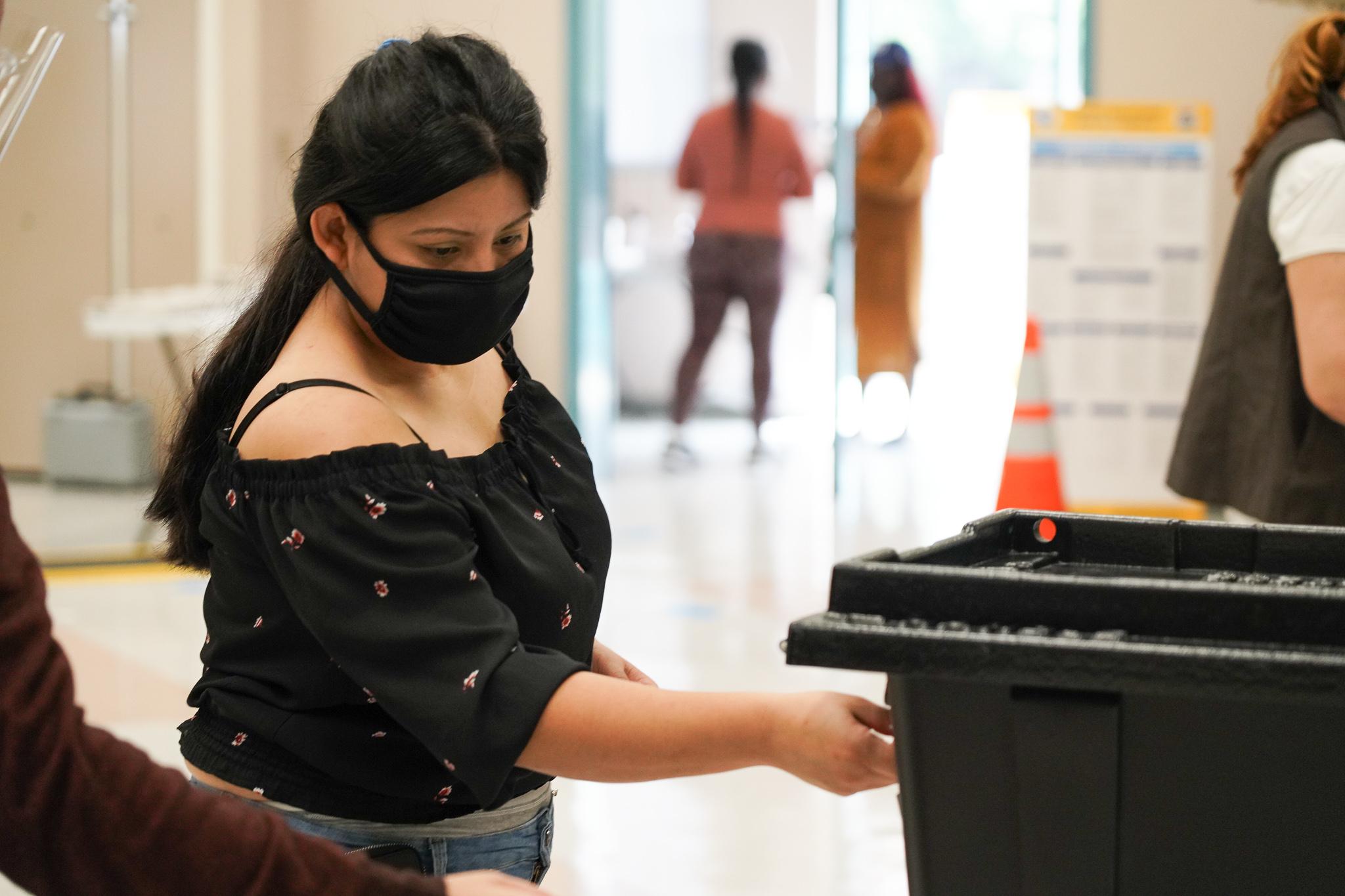 Meladis Romero, 32, originally from El Salvador drops off her mail in ballot in the Pico-Union area of Los Angeles.