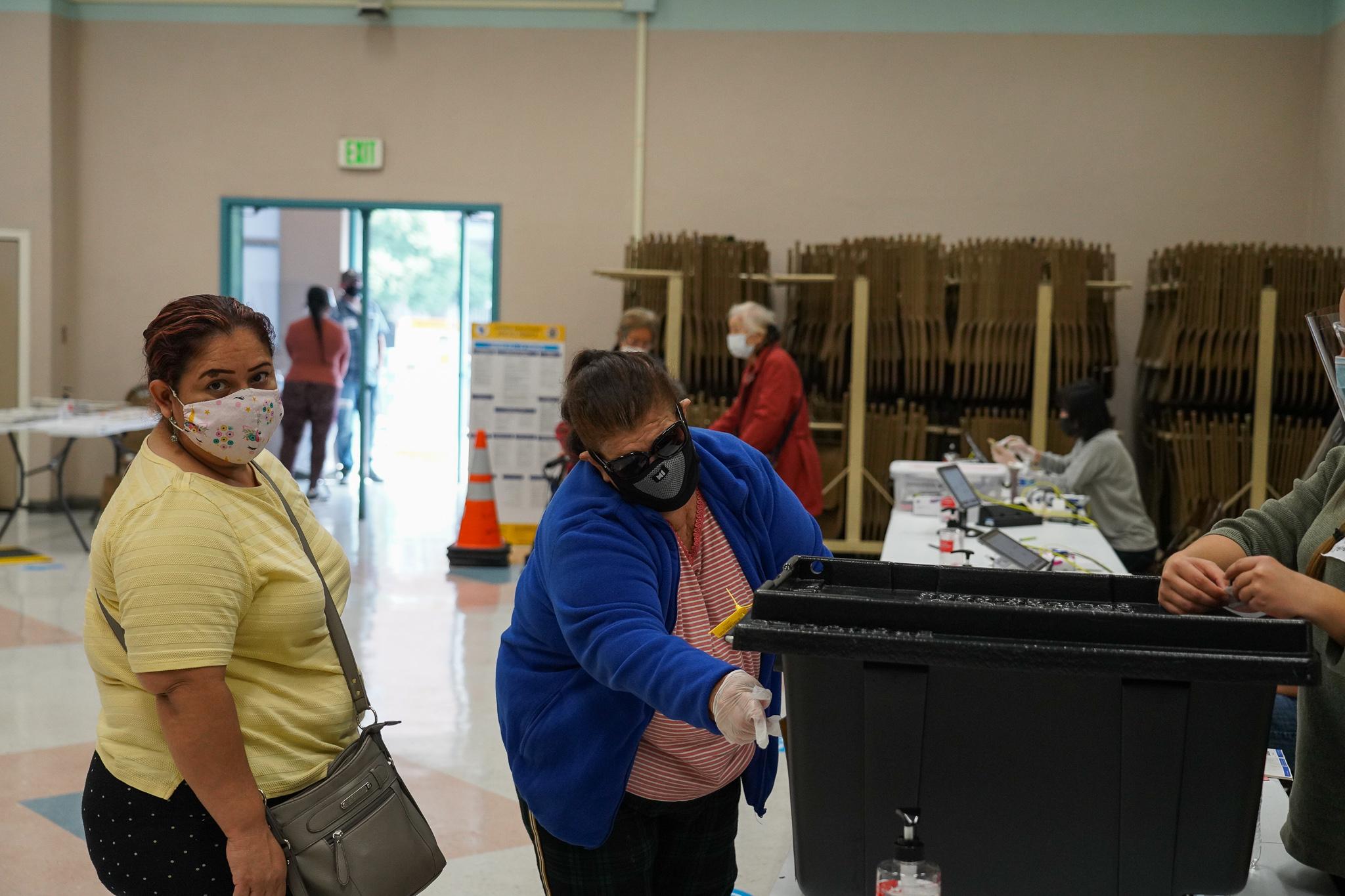 75-year-old Teresa Lopez (in blue sweater), originally from Sonsonate, El Salvador, casts her vote with the help of her caregiver.