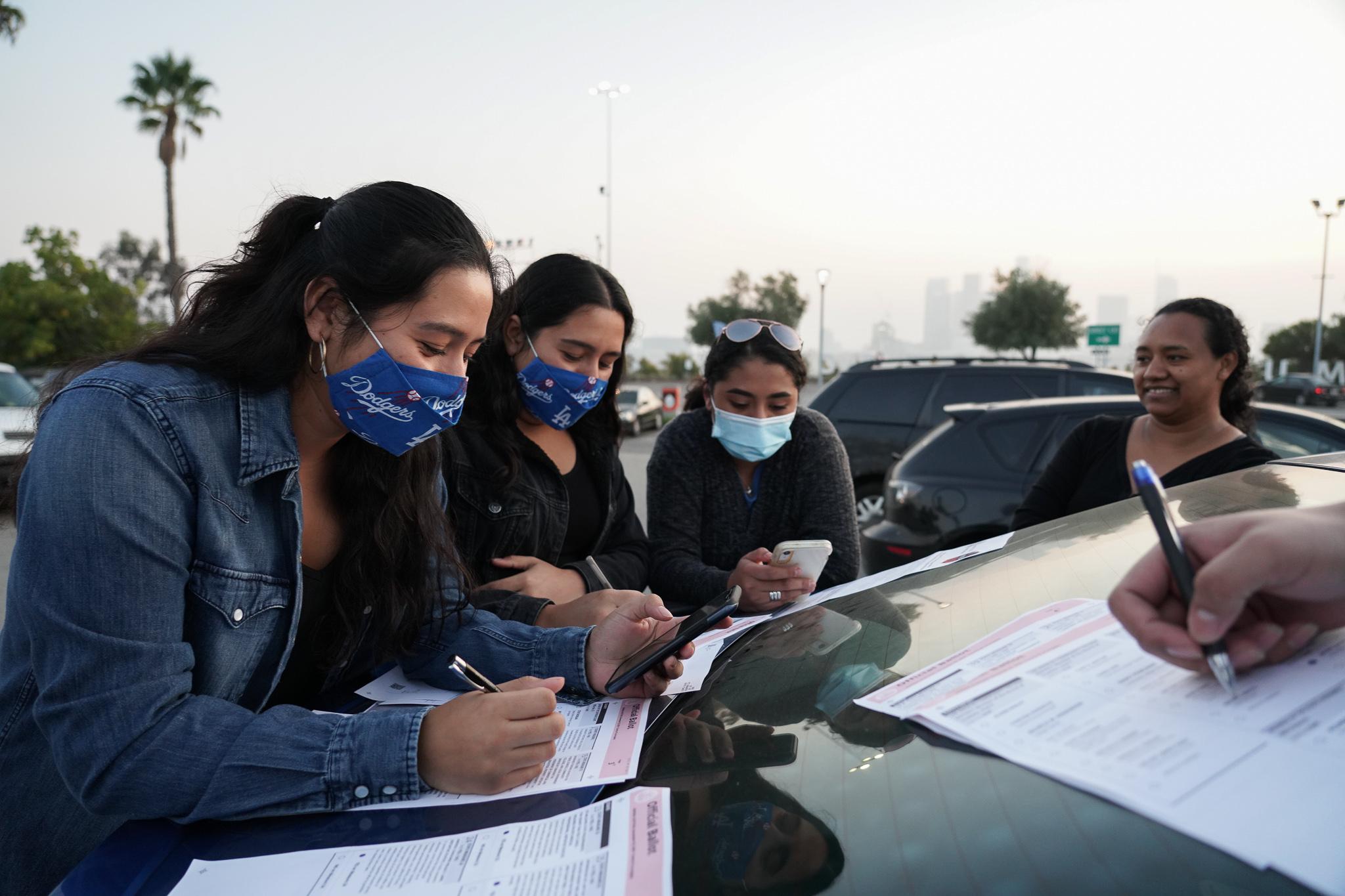 The Figueroa family, from left to right, 19-year-old twins Tatiana and Tiffany are aided by their 15-year-old sister, Karen, in deciding on the California propositions. Karen was in charge of researching on her phone what the propositions mean as their mother, Mirna, proudly looks on. The family uses the car