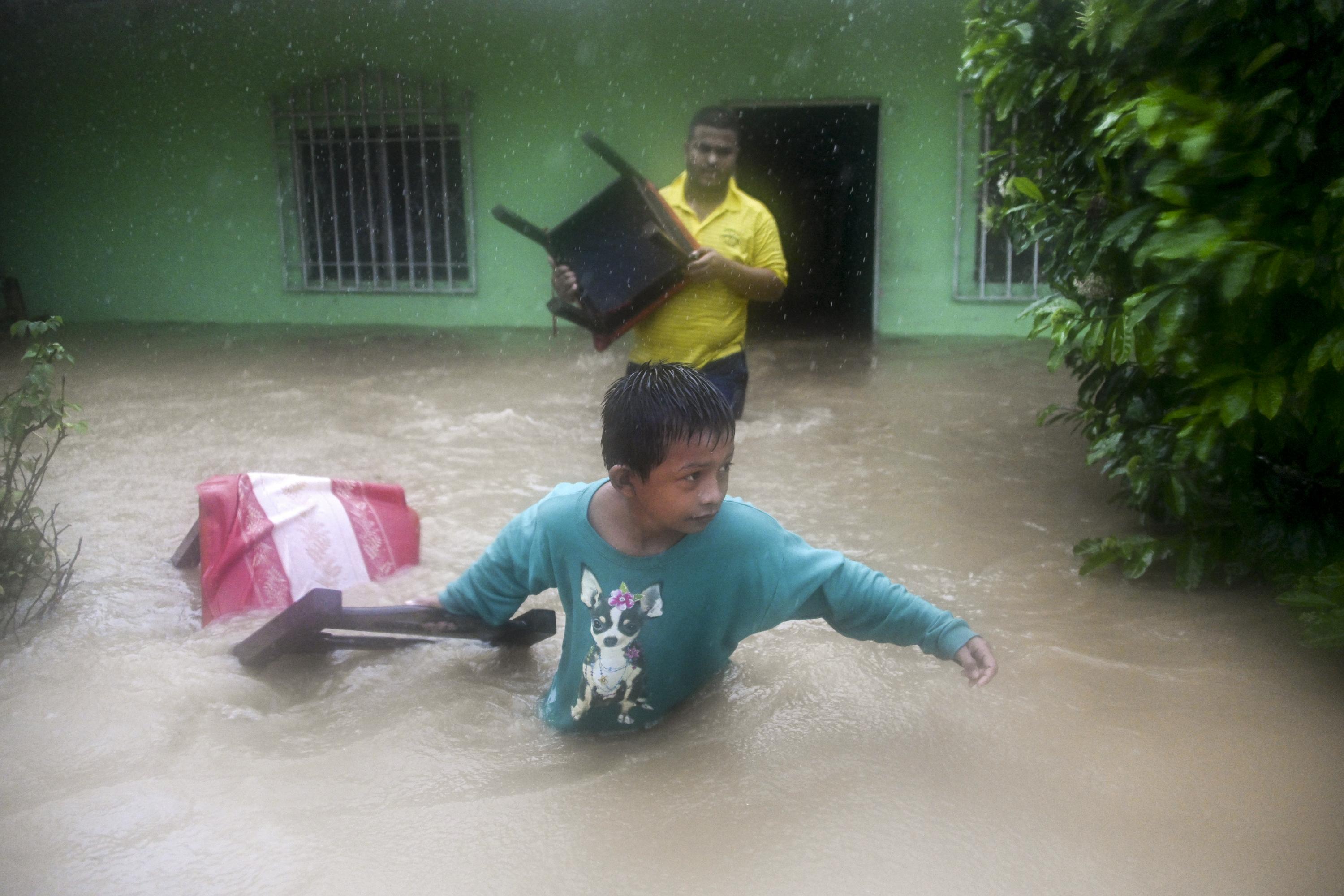 Un niño y un hombre salvan sillas de una casa inundada debido a las fuertes lluvias en Puerto Barrios, Izabal, 310 km al norte de la Ciudad de Guatemala el 5 de noviembre de 2020. Foto de Johan Ordoñez / AFP.