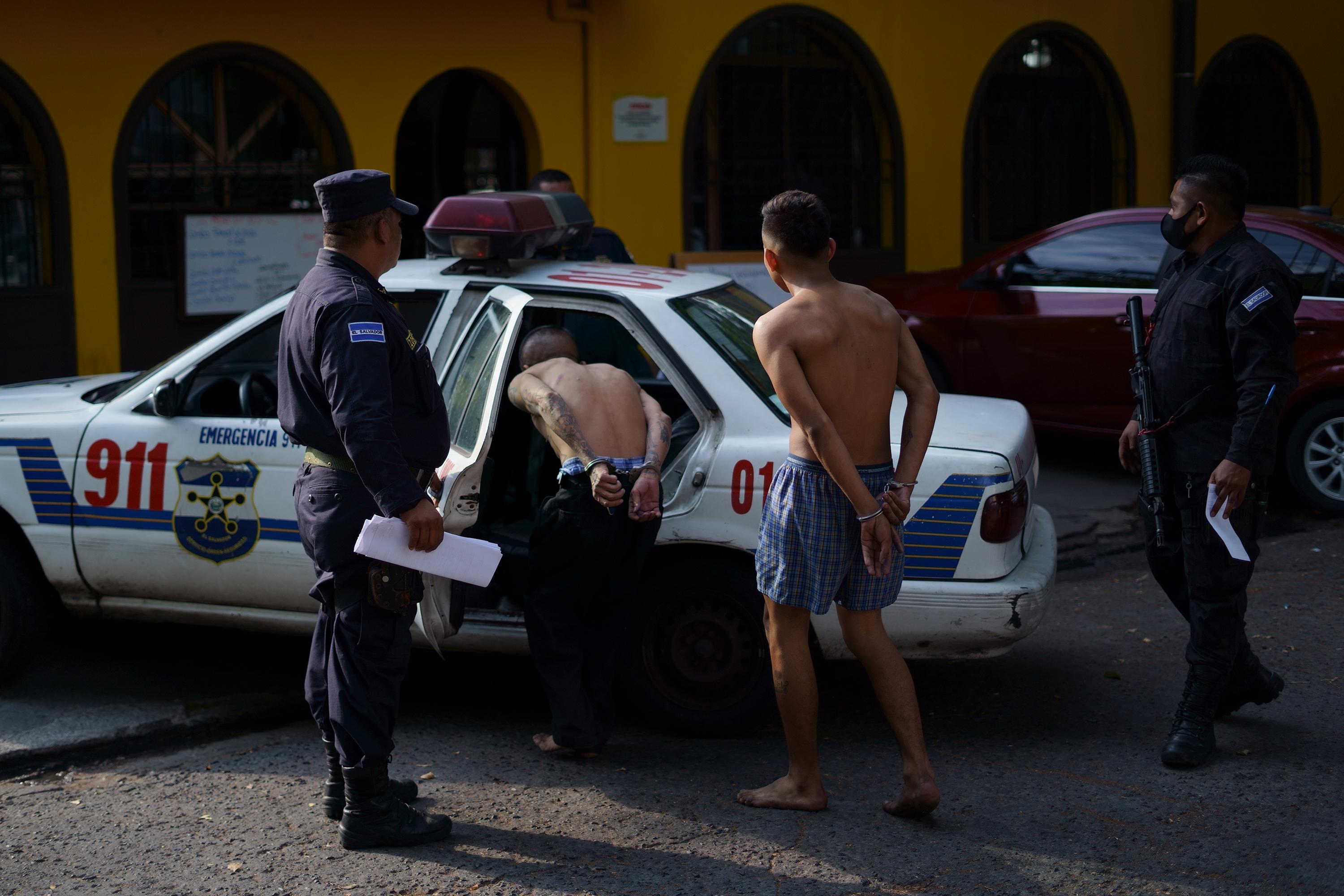 Agentes policiales custodian a dos de los detenidos durante el Régimen de Excepción. Ambos fueron presentados ante un defensor público en la Procuraduría General de la República, el 25 de abril de 2022. Foto de El Faro: Víctor Peña. 