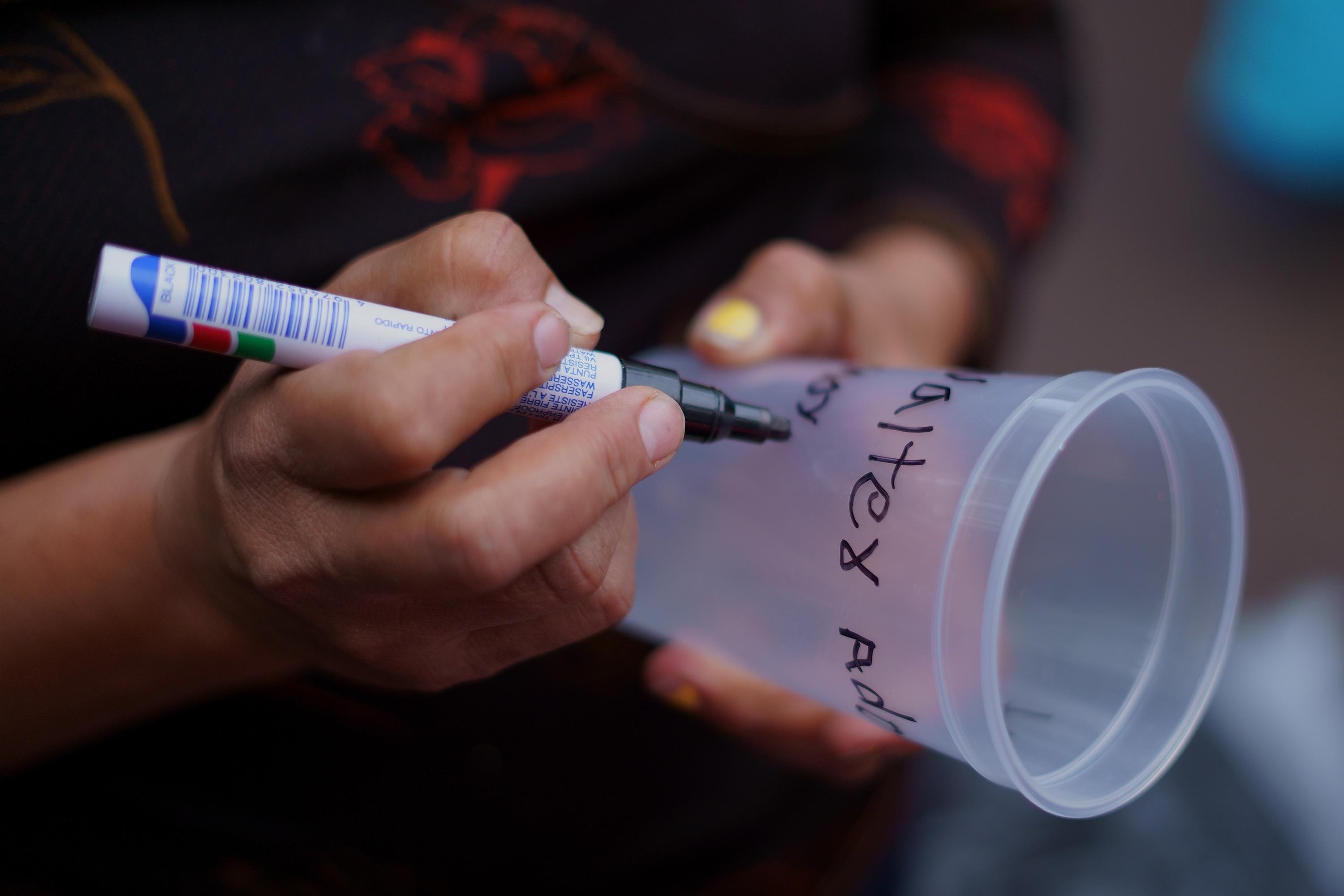 María Moreno writes the name of her only son on a plastic cup. She carries her own marker, so she doesn’t have to pay the $1.00 fee to rent one. María spent $30 on the last package she delivered to Izalco Prison for her 20-year-old son, arrested on May 17 in Santa Ana. María earns a living selling breakfast in her neighborhood, but she had to shut down her business, which is her only income, so she could travel to the prison. María spends about $4.00 on bus fare each time she travels to the prison.