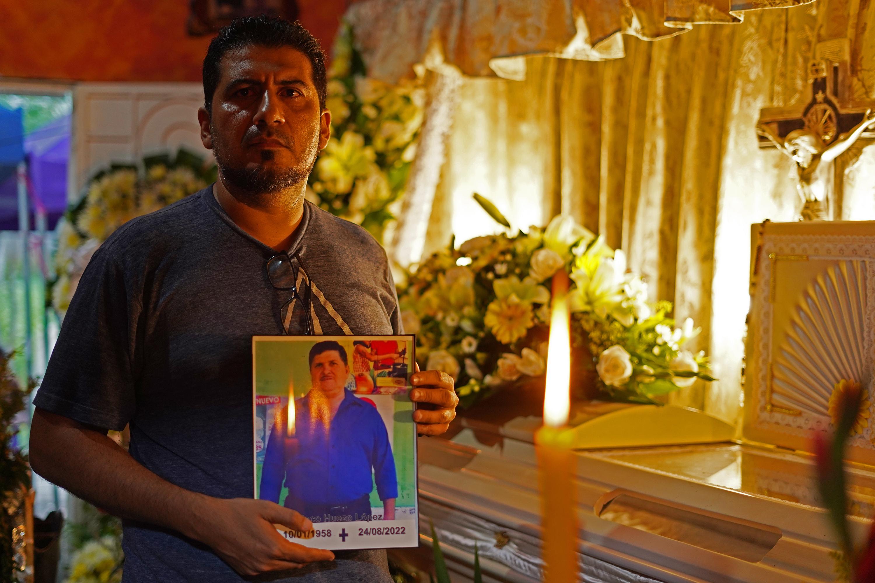 Durante el funeral, Francisco Huezo, de 43 años, muestra el retrato su padre, quien murió en el penal La Esperanza, dos meses después de haber sido capturado por el Régimen de Excepción. Foto de El Faro: Víctor Peña. 