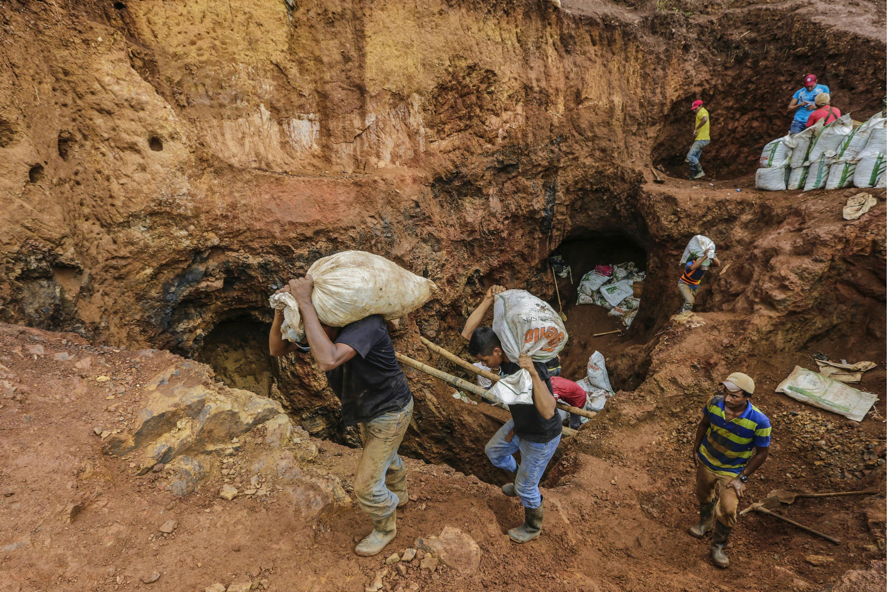 (FILES) In this file photo taken on March 07, 2017 miners carry sacks with rocks to be crushed, in order to extract gold, in the 