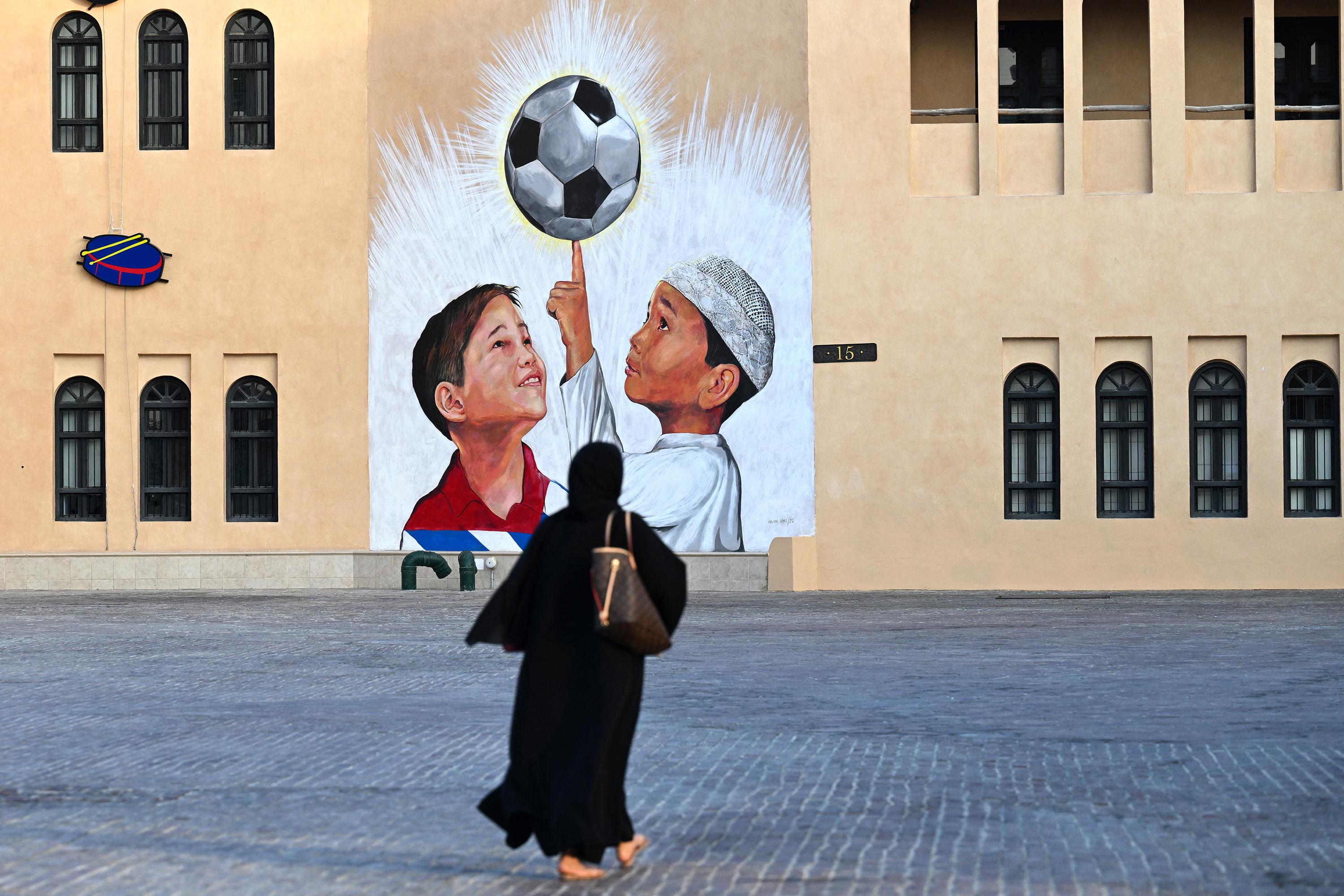 Una mujer pasa junto a un mural en Doha el 8 de noviembre de 2022, antes del torneo de fútbol de la Copa Mundial de la FIFA Qatar 2022. (Foto de Gabriel BOUYS / AFP)
