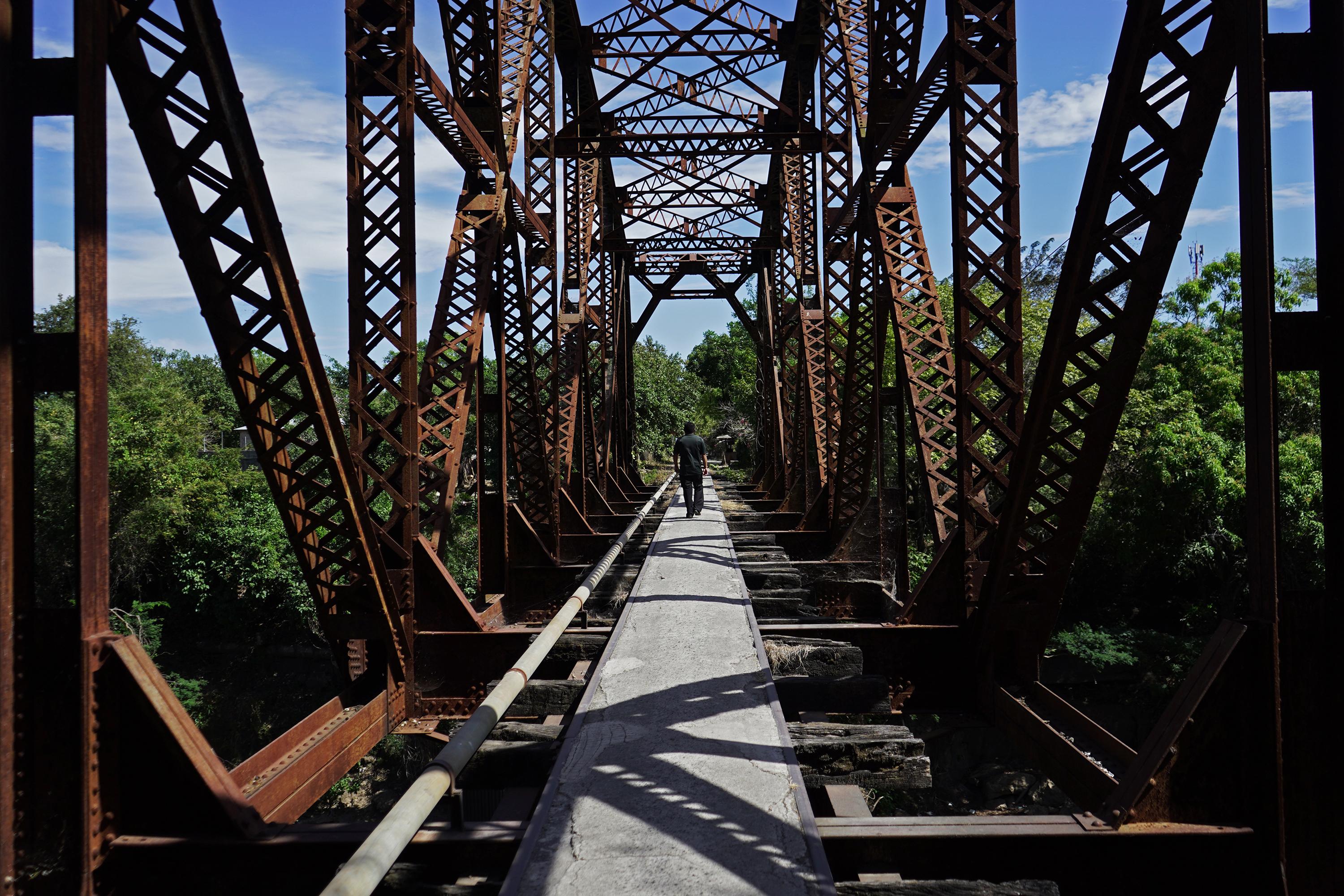 José Martínez walks along the Black Bridge that divides the communities La Presita and La Pradera in San Miguel. La Mirada Locos used to charge a toll to use the bridge. Photo: Víctor Peña/El Faro