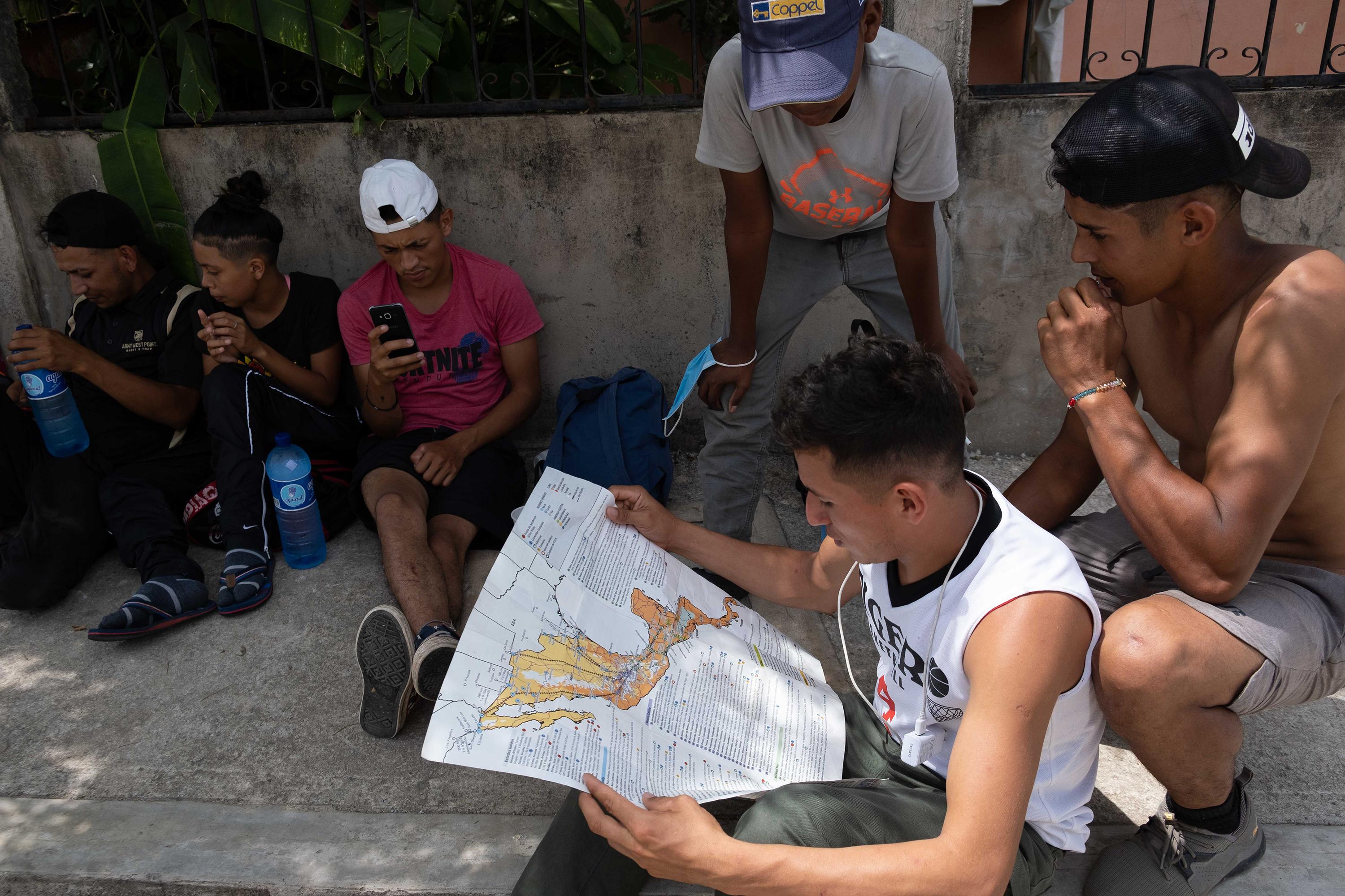 Un grupo de migrantes centroamericanos observan el mapa del territorio mexicano para planificar la ruta que tomarán en los siguientes días, mientras descansan frente al albergue Casa del Caminante, en Palenque, Chiapas, México. La segunda de izquierda a derecha es Amaya. Foto de El Faro: Isabel Mateos. 