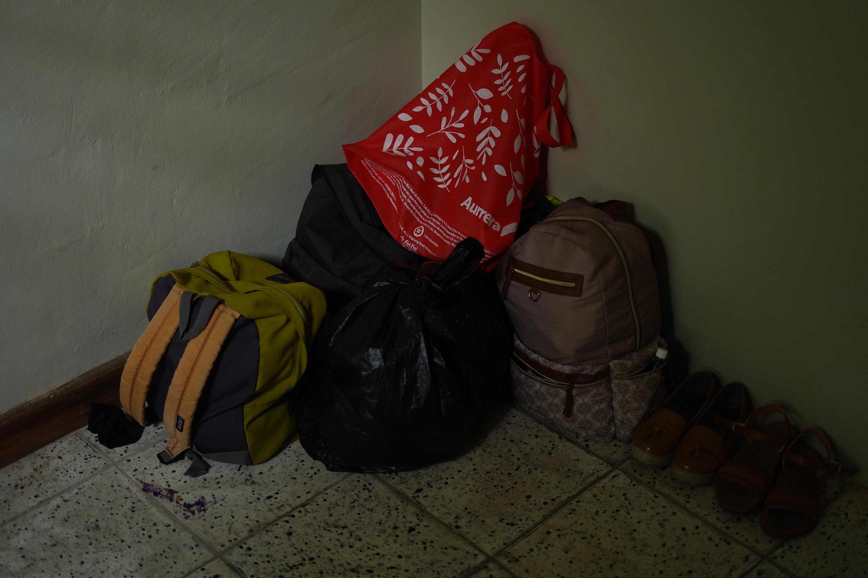 The family keeps their luggage organized, in case they have to leave in a hurry. Here, backpacks are arranged in the corner of a small room they share in a house. Photo: Víctor Peña/El Faro