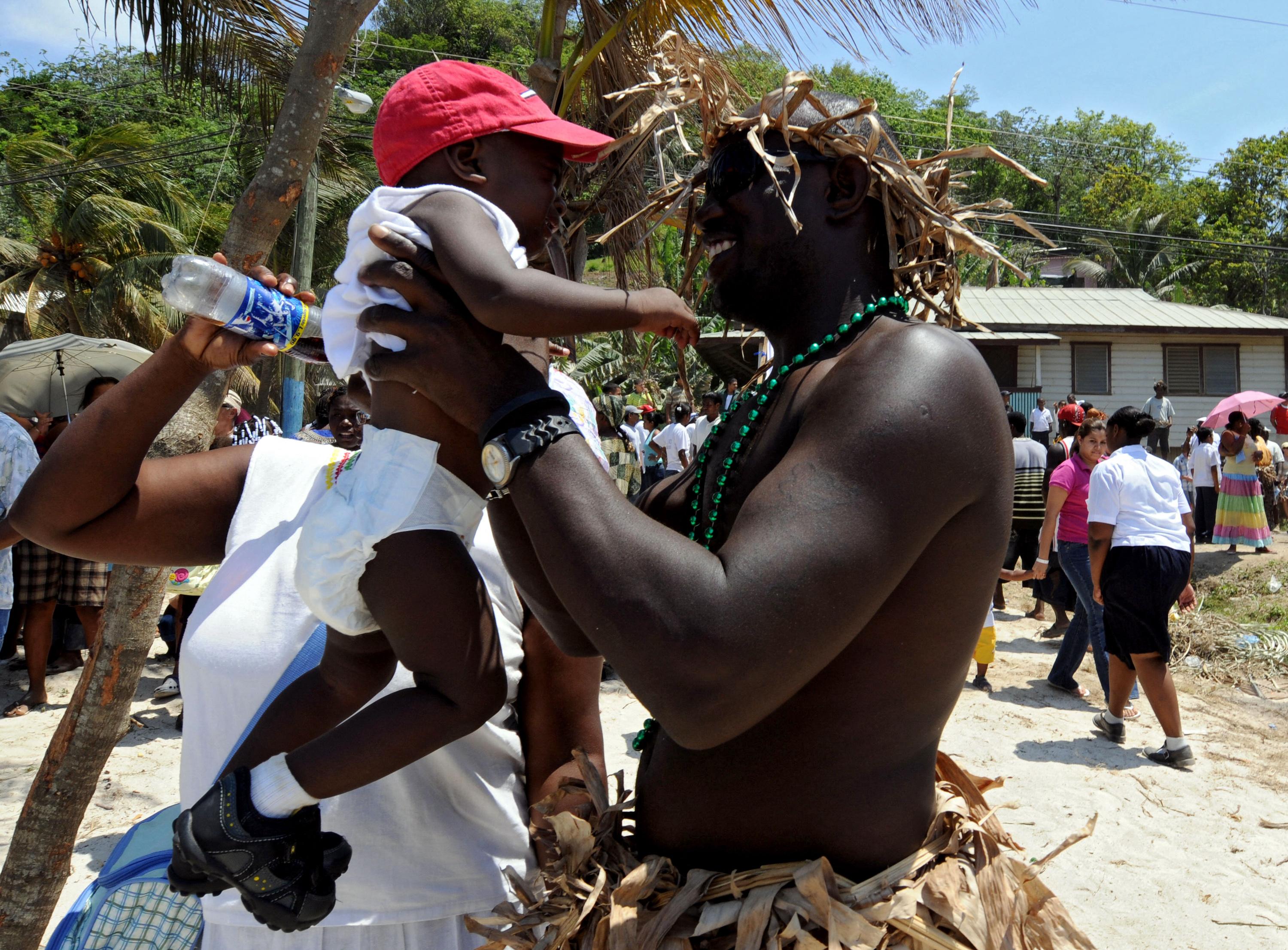 A Garifuna man holds his baby during a ceremony to commemorate 211 years since their arrival to Punta Gorda from St. Vincent on April 12 2008 in Roatan, department of Bahia Islands, Honduras. At the time, the Garifuna people were demanding productive projects from the government of then-head of state Manuel Zelaya, husband of current President Xiomara Castro, to contribute to the development of their community. Photo: Orlando Sierra/AFP