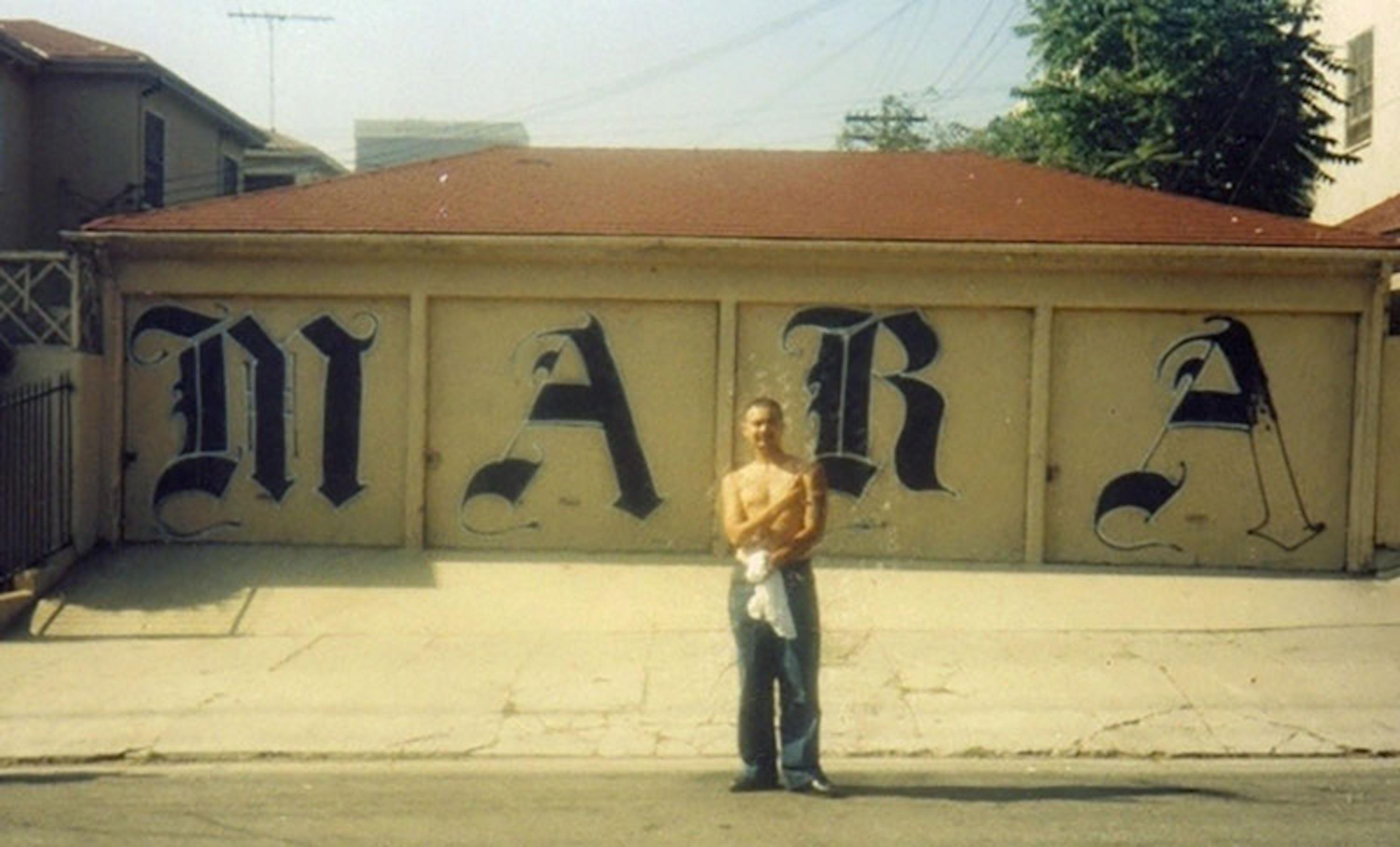 Stranger, a member of the Adams Locos clique of the Mara Salvatrucha, in front of a gang mural near Norton Street in Los Angeles. The Adams Locos, founded in the early 90s, was one of the last MS-13 cliques to emerge from Los Angeles. Photo El Faro archive