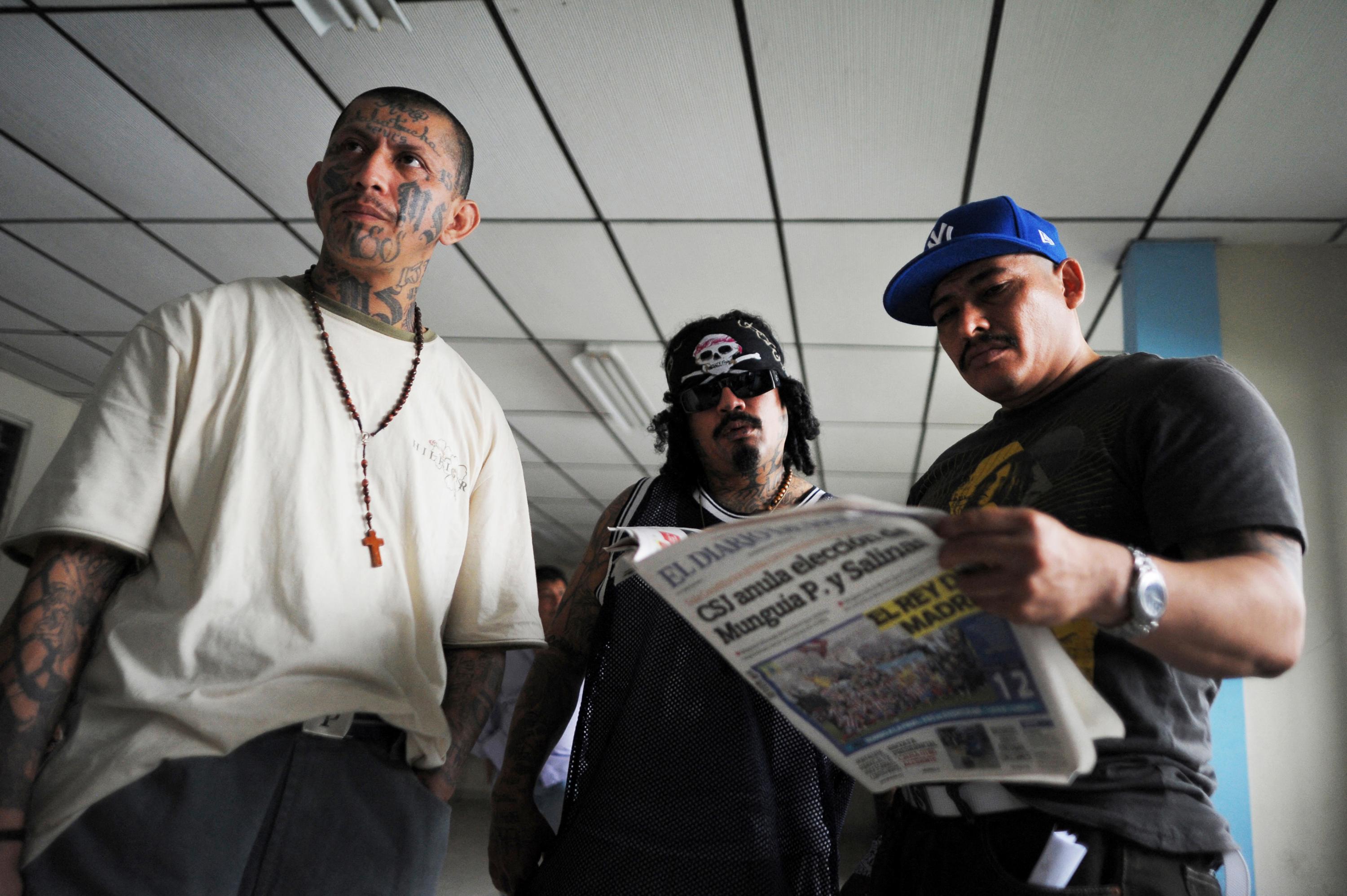 Élmer Canales Rivera, Crook, lee un periódico a la par de Saul Antonio Turcios and Tiberio Ramirez (izquierda), todos líderes de la MS-13, luego de una conferencia de prensa en 2013. Foto de El Faro: AFP.