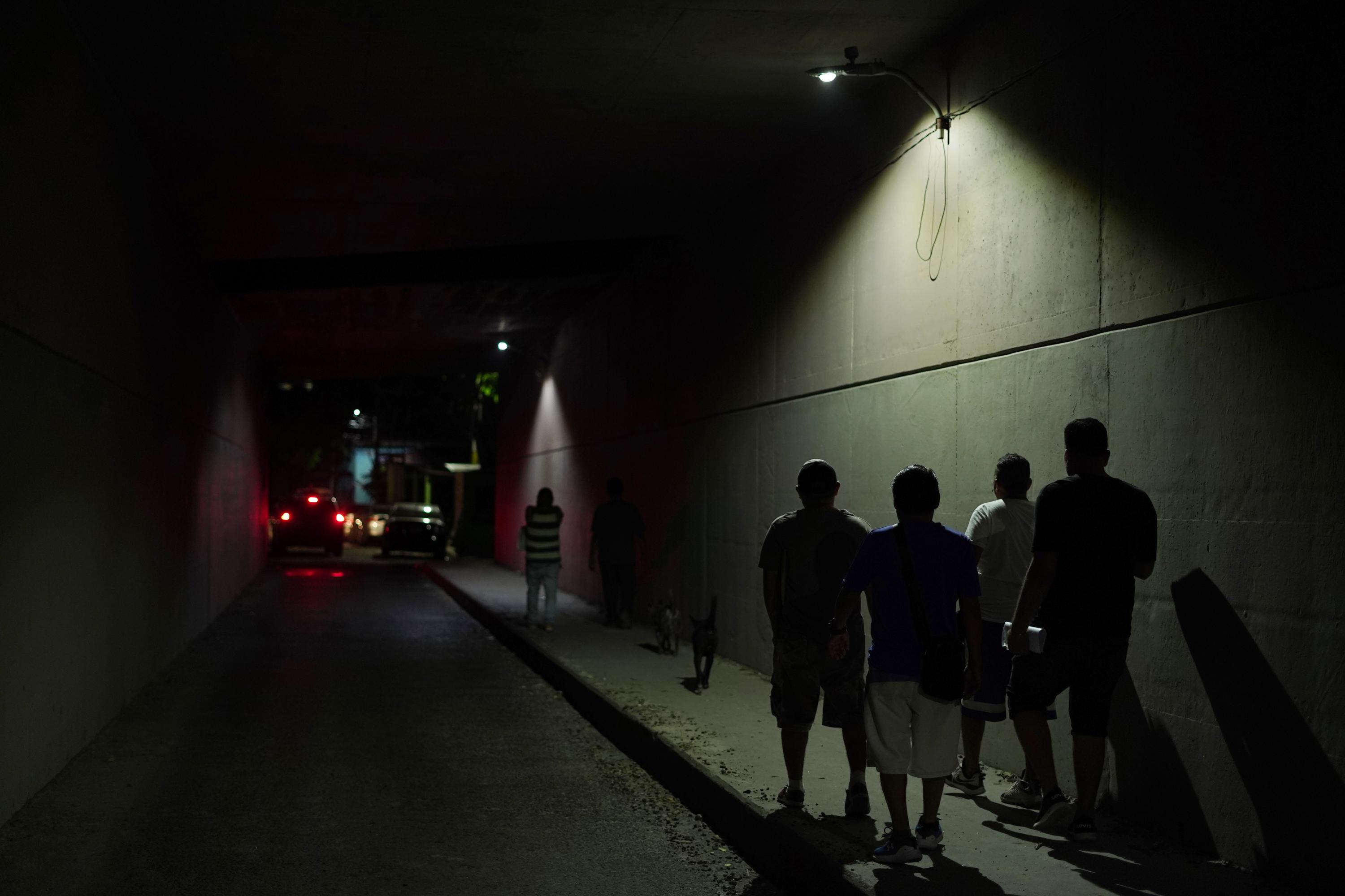 Habitantes de Las Cañas caminan por el túnel de la entrada a la comunidad, bajo la carretera de Oro. Esa área era una frontera invisible entre ambas pandillas y era intransitable en horas nocturnas. Foto de El Faro: Víctor Peña.
