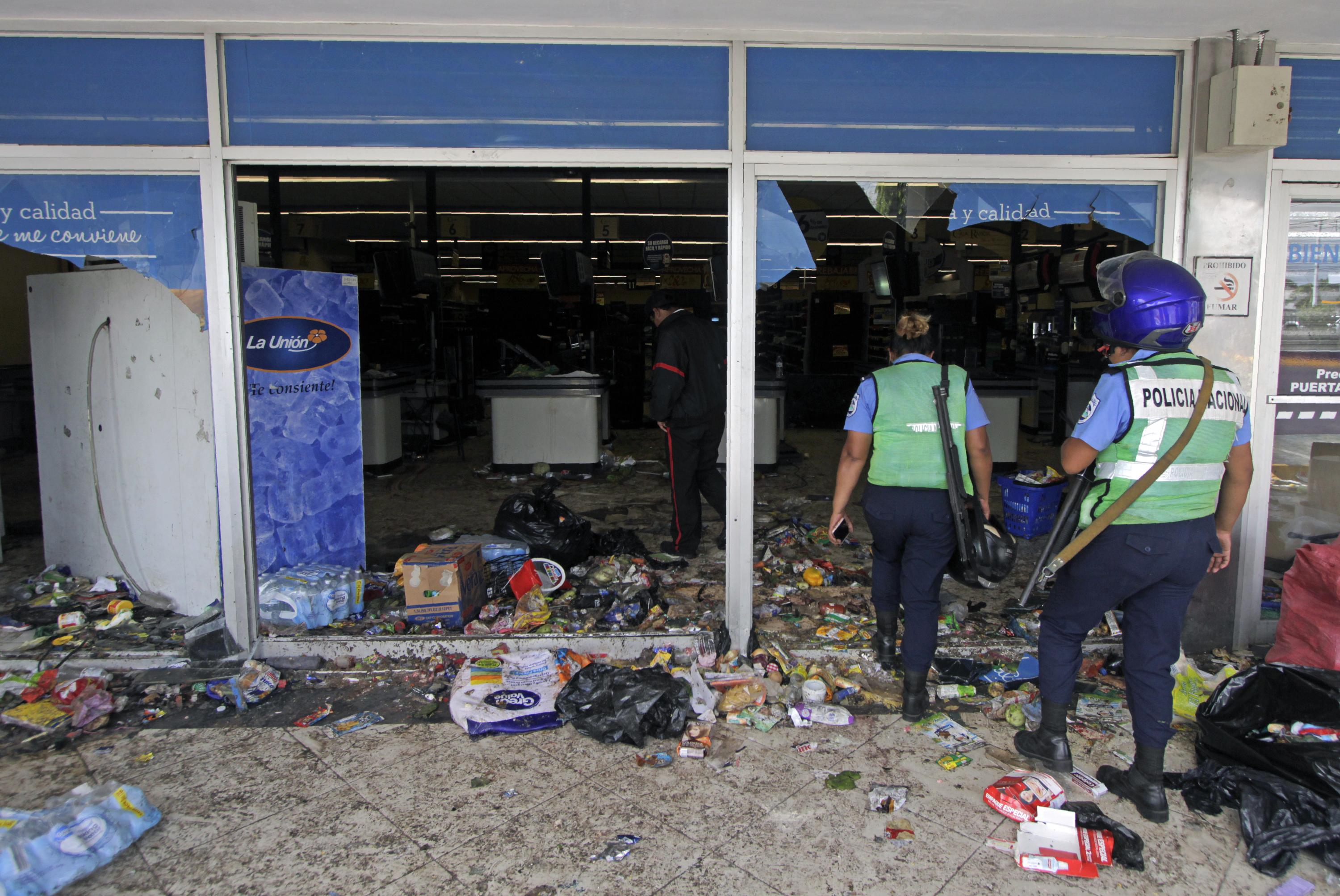 Policías ingresan a un supermercado después de ser saqueado durante las protestas contra las reformas al Instituto de Seguridad Social (INSS) en Managua el 22 de abril de 2018. El presidente de Nicaragua, Daniel Ortega, anunció el domingo desechar la reforma. / AFP PHOTO / INTI OCON