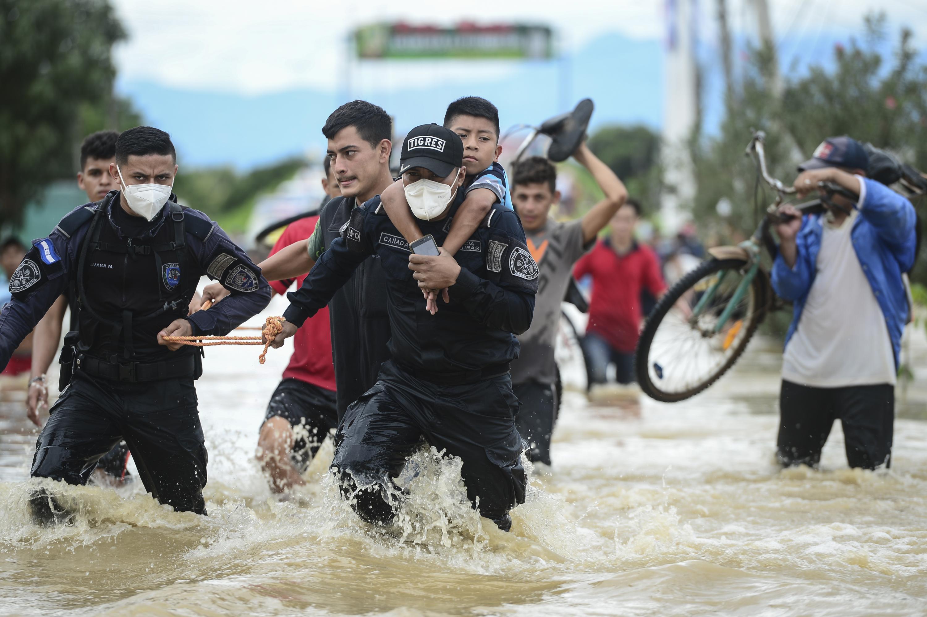Policías hondureños ayudan a evacuar a personas tras el desborde del río Ulúa por las fuertes lluvias provocadas por el huracán Eta, ahora degradado a tormenta tropical, en la ciudad de El Progreso, departamento de Yoro, 260 kms al norte de Tegucigalpa. Foto de Orlando Sierra / AFP