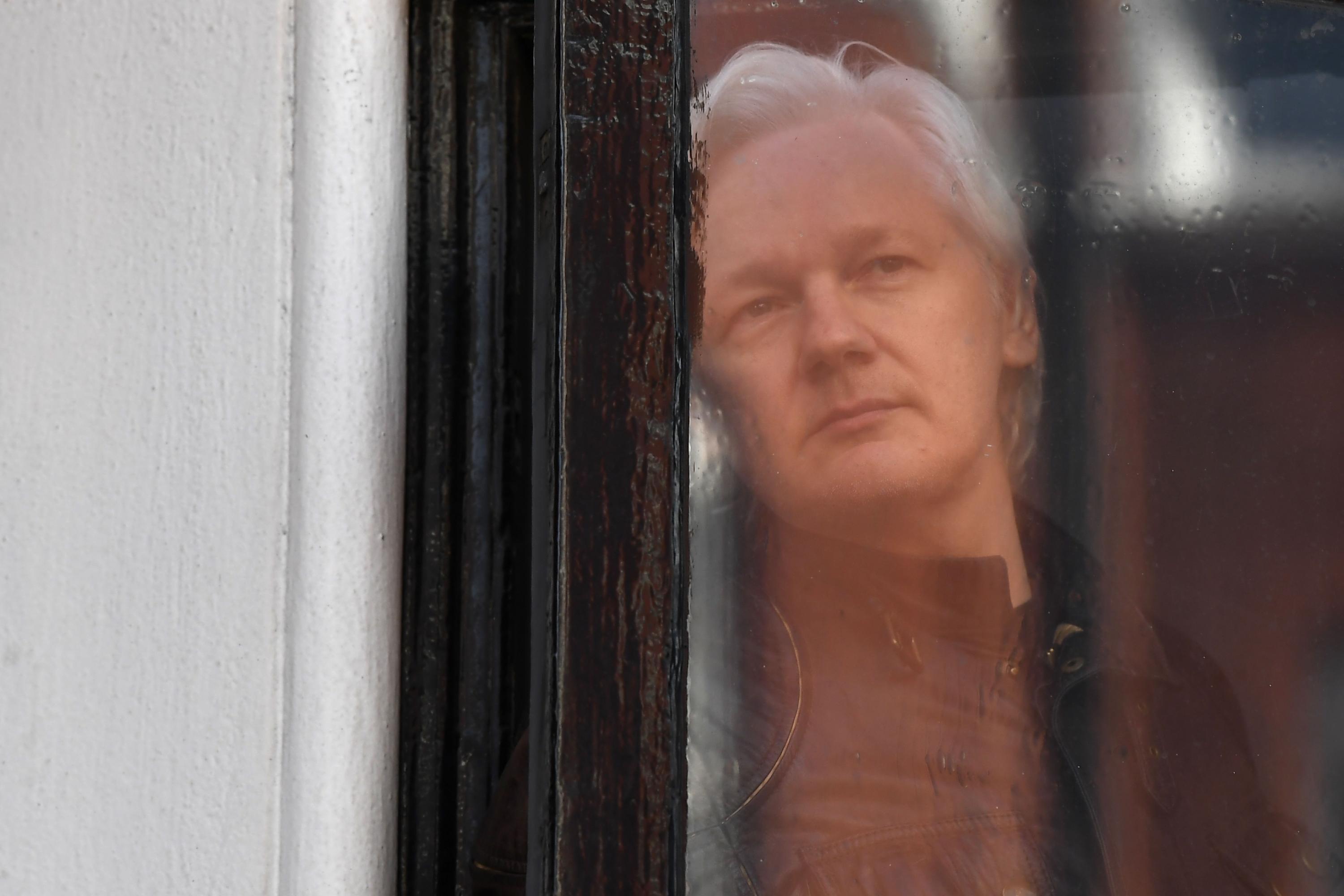 (FILES) In this file photo taken on May 19, 2017 Wikileaks founder Julian Assange look out from a window at the Embassy of Ecuador in London. - British police have arrested WikiLeaks founder Julian Assange at Ecuador