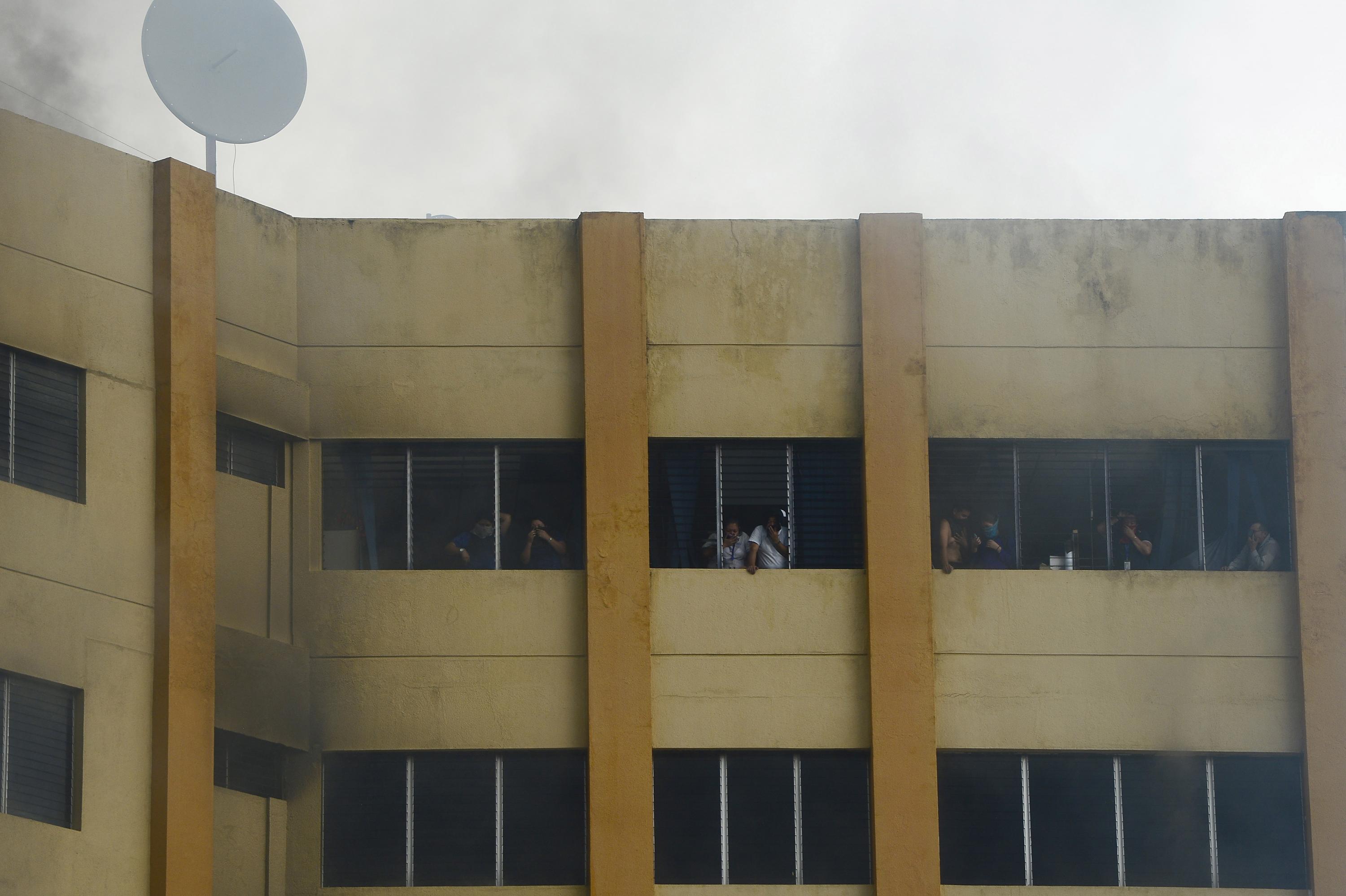 Empleados del Ministerio de Hacienda atrapados en el piso superios de la torre tres, minutos después de un voraz incendio que afecto los niveles 4, 5 y 6 del edificio. / AFP PHOTO / Marvin Recinos.