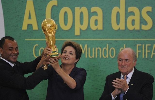 Dilma Rousseff, presidenta de Brasil y candidata a la reelección, levanta la copa del Mundial de Fútbol bajo la mirada complaciente de Joseph Blatter, presidente de la FIFA. Foto archivo El Faro.