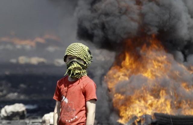 Un niño con el rostro cubierto con una kufiya permanece cerca de unas llantas en llamas durante una manifestación en el pueblo Kfar Qaddum, en el territorio palestino de Cisjordania. Foto archivo El Faro.