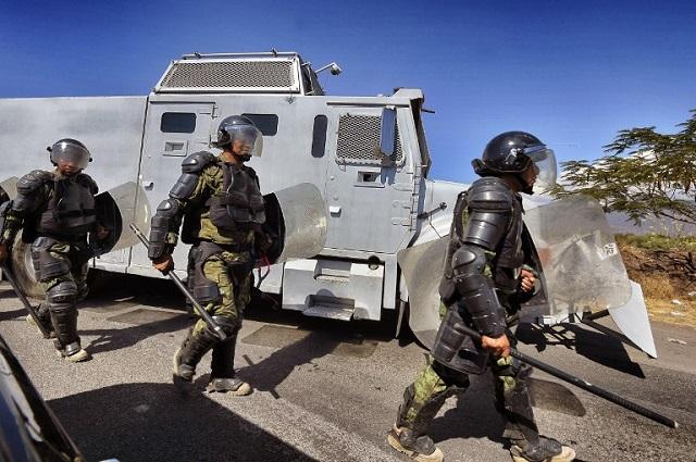 A group of Mexican soldiers with riot trucks take positions at the entrance to the Apatzingan community on January 10, 2015. A deadly clash erupted on January 6th between federal forces and civilians in Apatzingan, a former Knights Templar stronghold. Officials say at least nine people died after federal police and soldiers took back control of the City Hall from a group that had been occupying it since last December. AFP PHOTO/Alfredo ESTRELLA