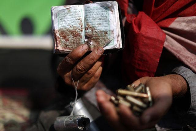 Un musulmán sostiene con una mano una copia del Corán manchada de sangre, y con la otra, casquillos de bala. Foto archivo El Faro.