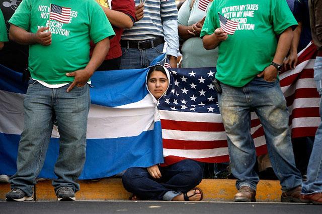 Una joven salvadoreña se arropa con las banderas de Estados Unidos y El Salvador durante una manifestación de 2007 en Manassas, Virginia, contra medidas para frenar la migración. Foto AFP/Chip Somodevilla
