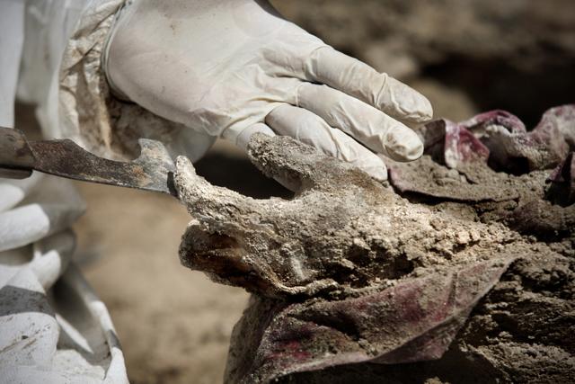 Detalle de una excavación. Ticas parece estrechar la mano de un cadáver momificado. 