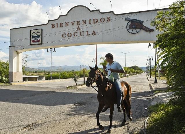Un hombre entra a caballo bajo el rótulo que indica la entrada a Cocula, municipio de Guerrero en el que en 2013 hubo un secuestro masivo similar al de Iguala. Foto Ronaldo Schemidt (AFP).