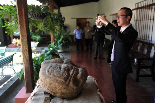 Un arqueólogo japonés toma fotografías de las cabezas descubiertas en una finca cafetalera de Chalchuapa, en Santa Ana. Foto José Cabezas (AFP)﻿" /></div> <figcaption class=